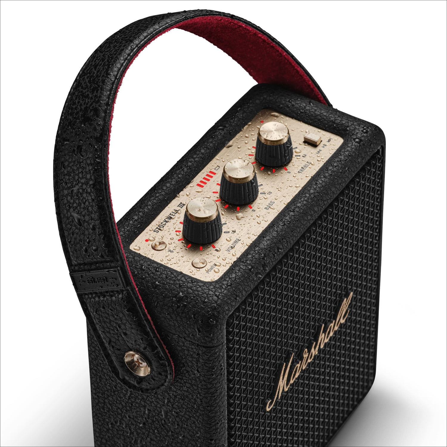 Black portable Marshall speaker with gold knobs and water droplets on its surface.