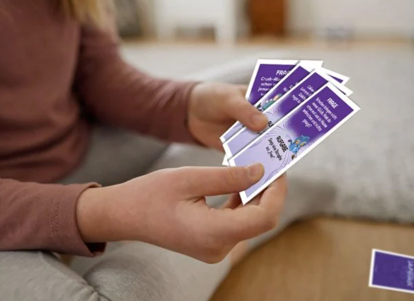 Eine Person hält mehrere violette Spielkarten in den Händen.