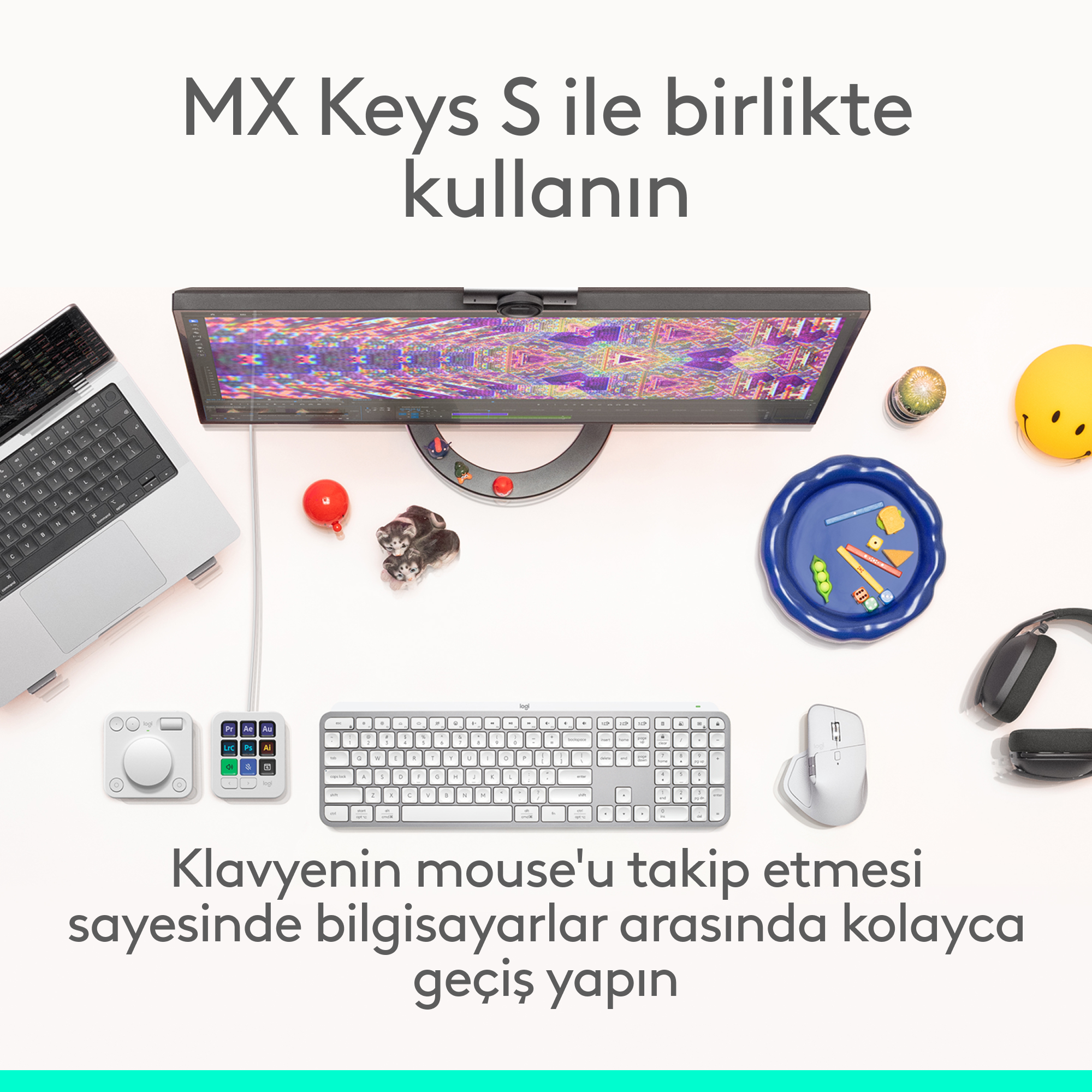 Monitör, klavye, fare, dizüstü bilgisayar, kulaklık ve renkli aksesuarların yer aldığı masanın üstten görünümü.