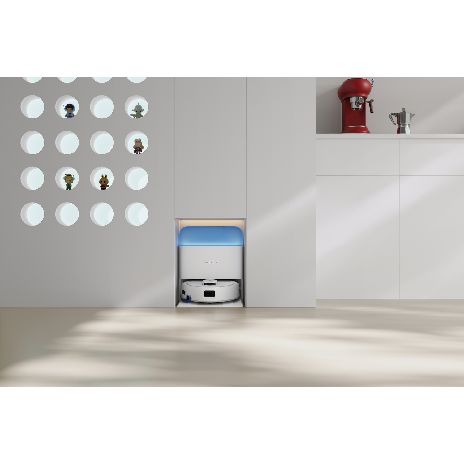 Un robot aspirapolvere bianco nella sua stazione di ricarica in una cucina minimalista moderna con elettrodomestici rossi.