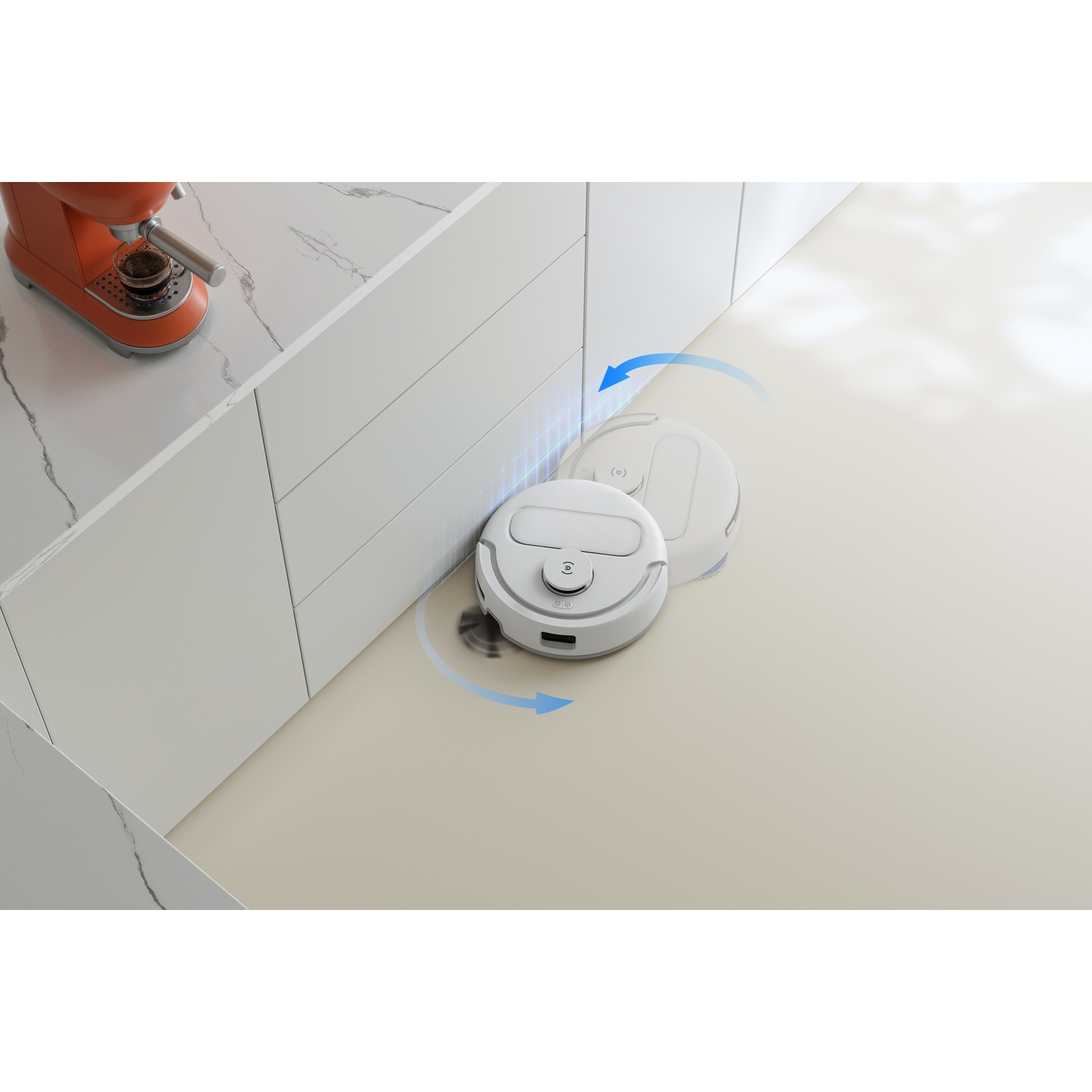 Un robot aspirapolvere bianco pulisce il pavimento in una cucina moderna con mobili bianchi.