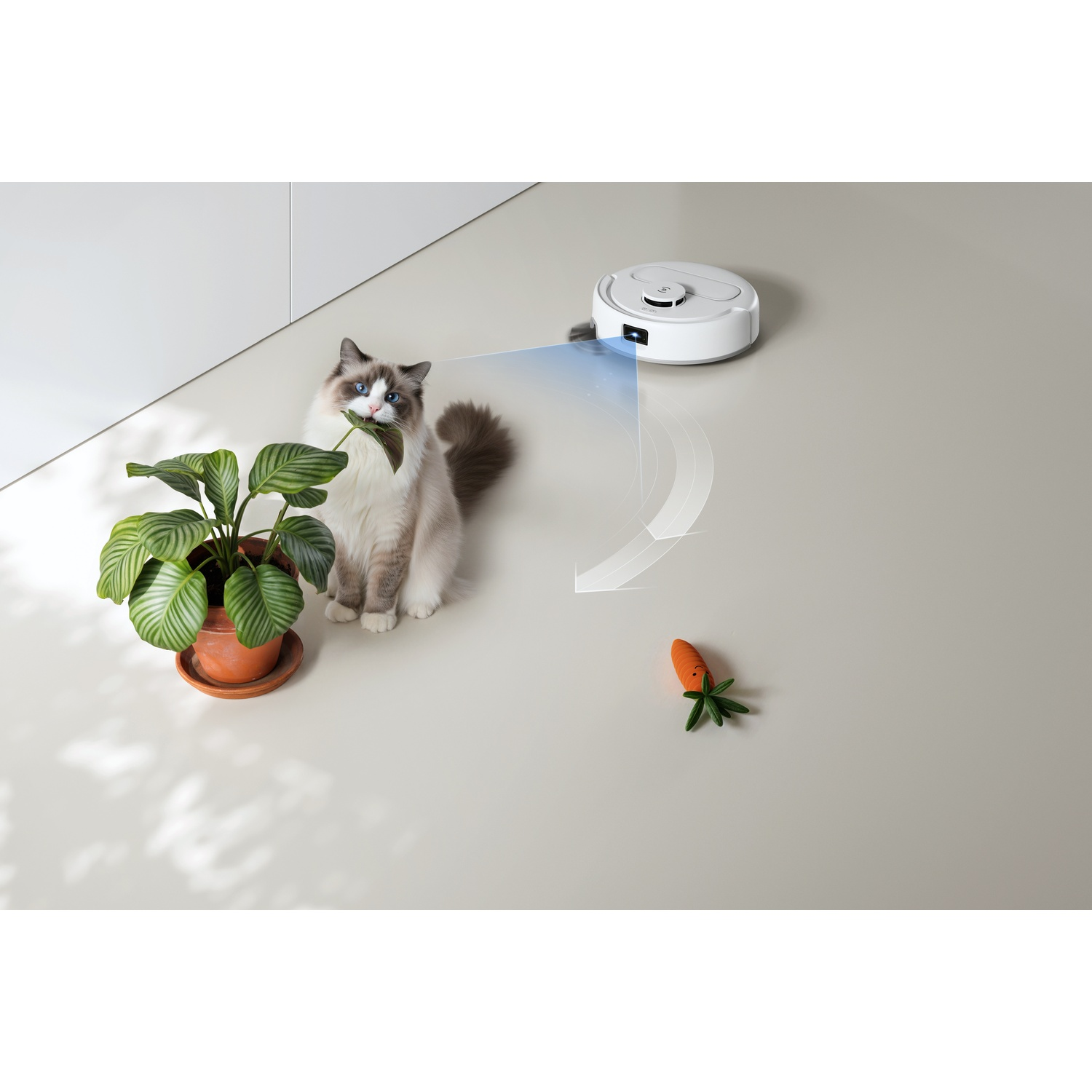 Un robot aspirapolvere scansiona un gatto che morde una pianta in vaso vicino a una carota giocattolo.