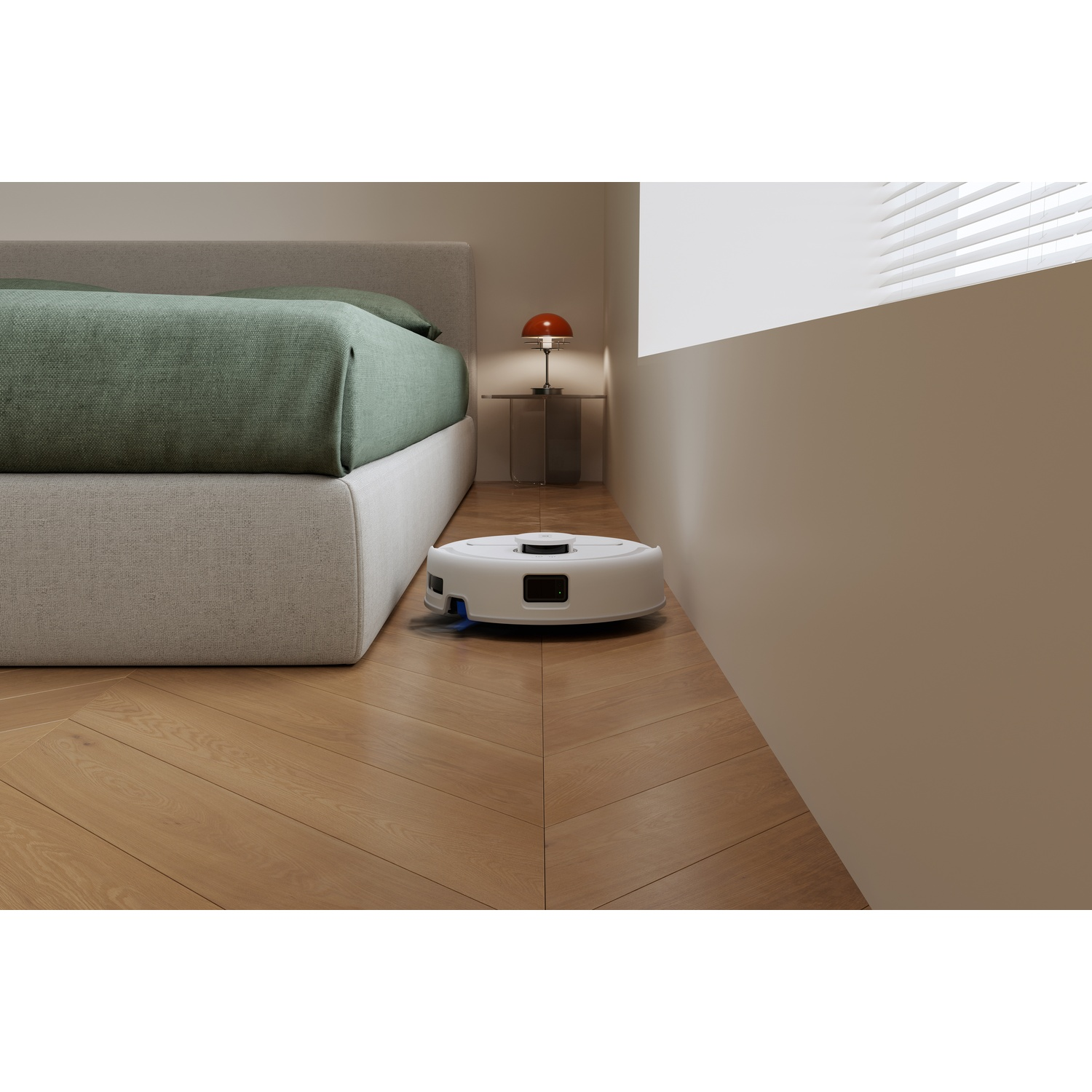Un robot aspirapolvere bianco pulisce il pavimento in legno di una camera da letto vicino a un letto con lenzuola verdi.
