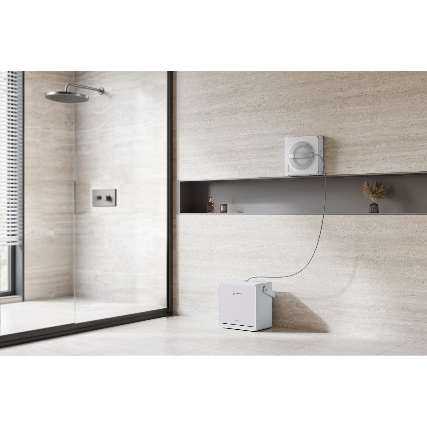 Un robot pulisci vetri bianco pulisce una parete del bagno, collegato a una piccola base a terra.