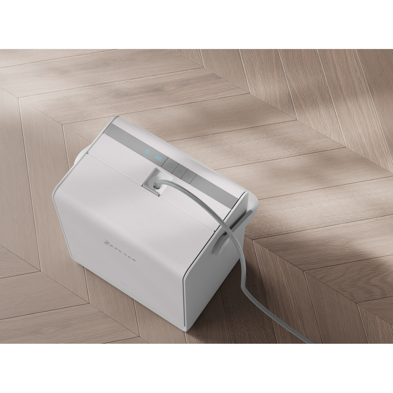 Un dispositivo portatile bianco con display digitale su un pavimento in legno con un cavo collegato.