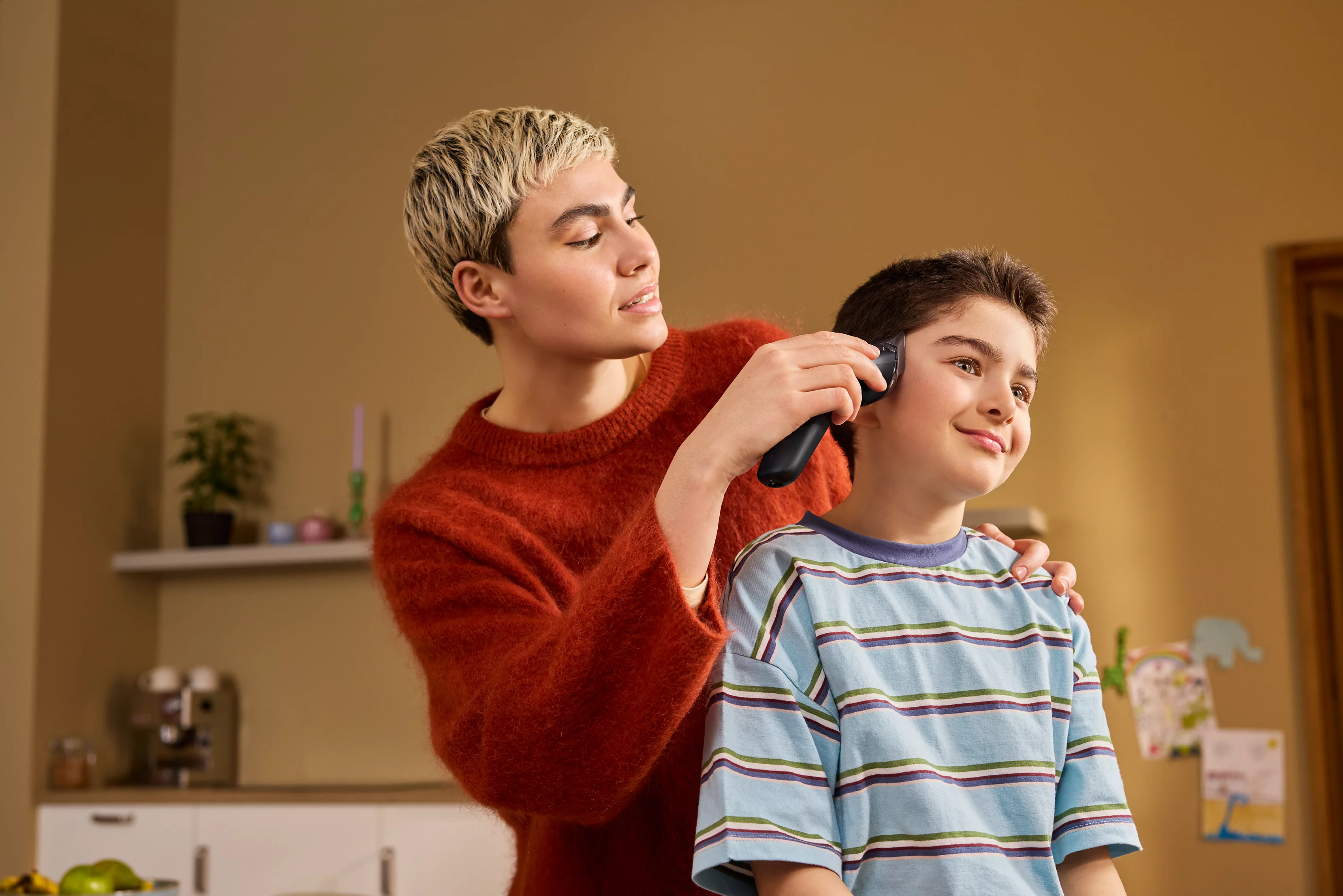 Eine Person schneidet mit einer Haarschneidemaschine die Haare eines jungen Jungen.