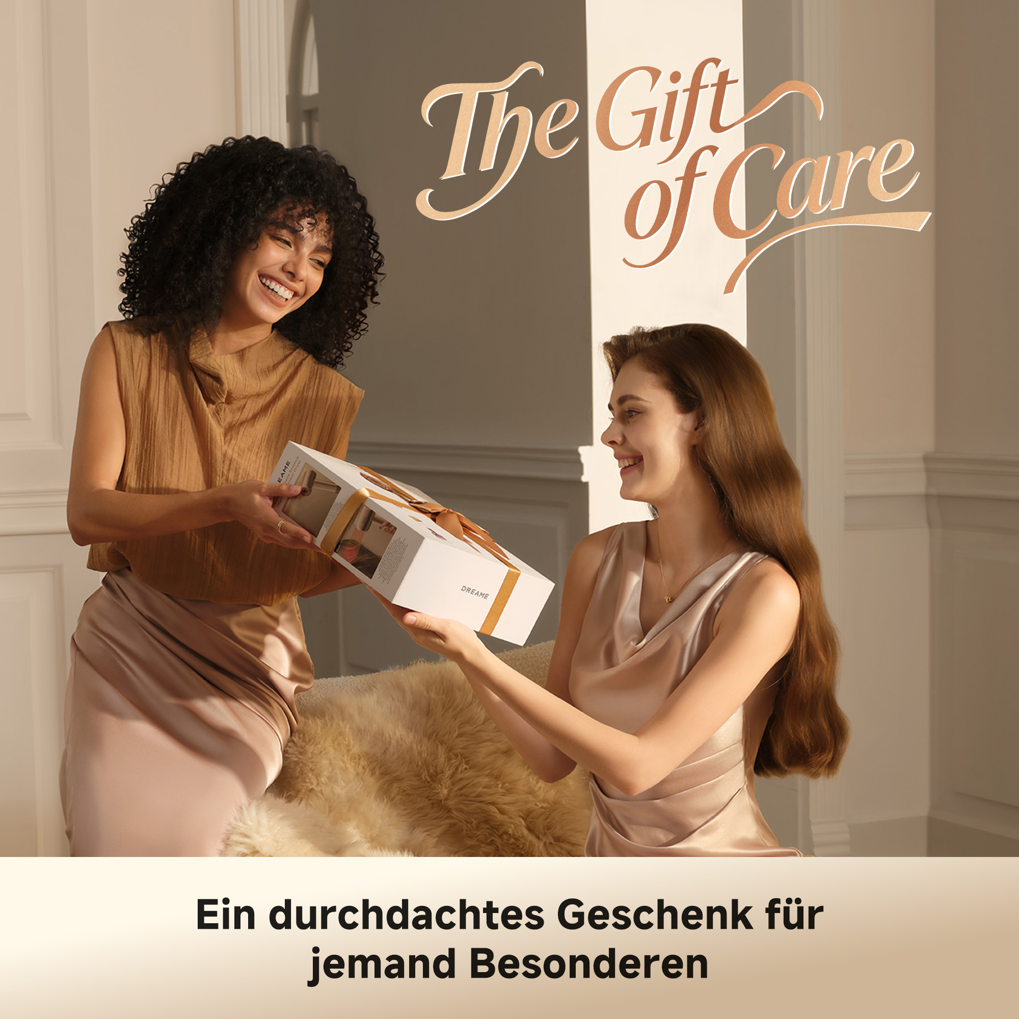 Eine Frau mit dunklen Locken schenkt einer sitzenden Frau mit braunen Haaren ein Geschenkpaket.