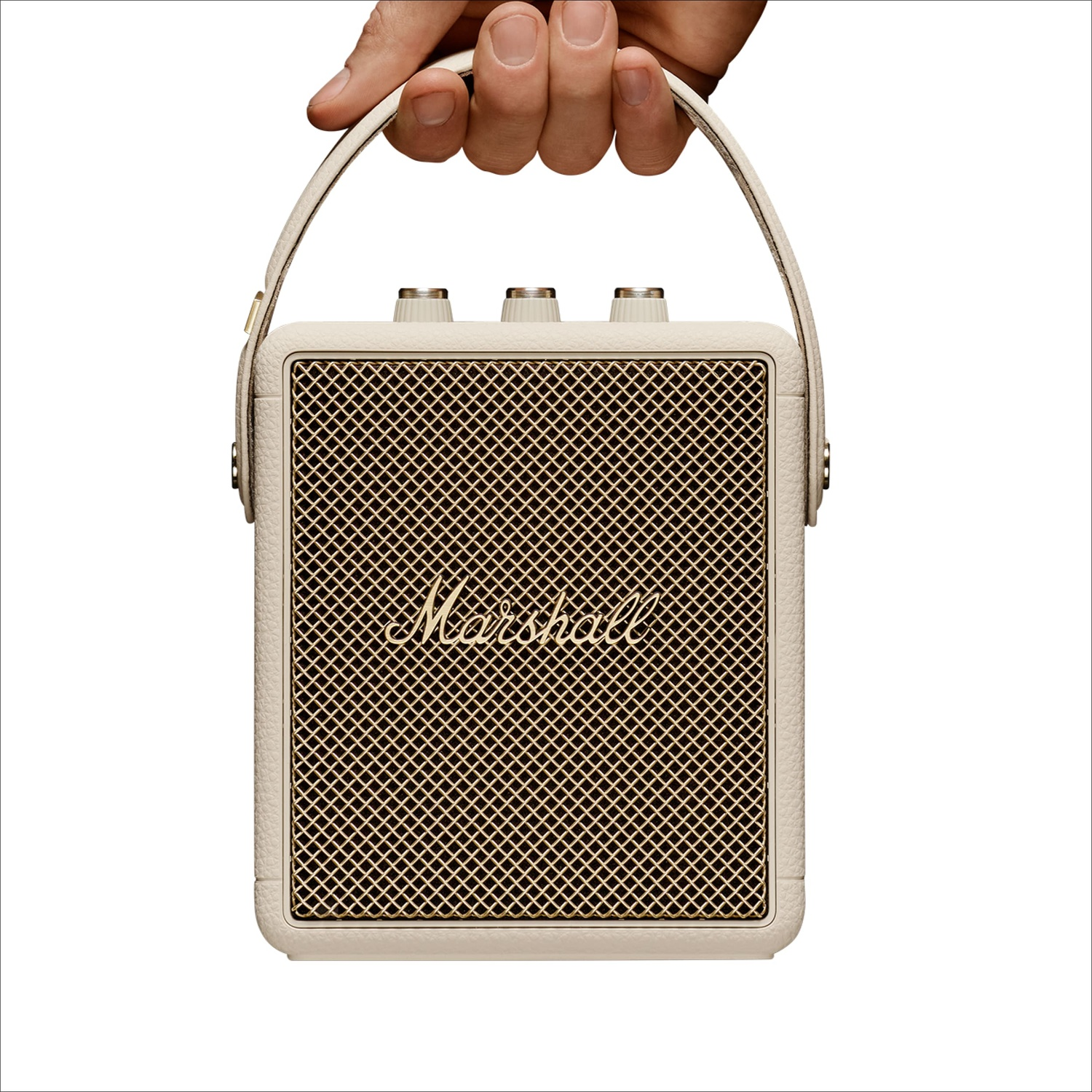 A hand holds a portable cream-colored Marshall speaker by its strap against a white background.