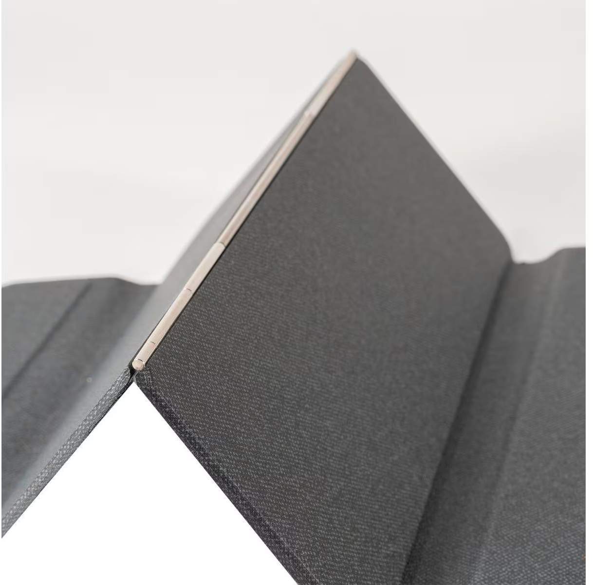 Gros plan d'un support de tablette noir pliable avec charnière métallique, sur fond clair.
