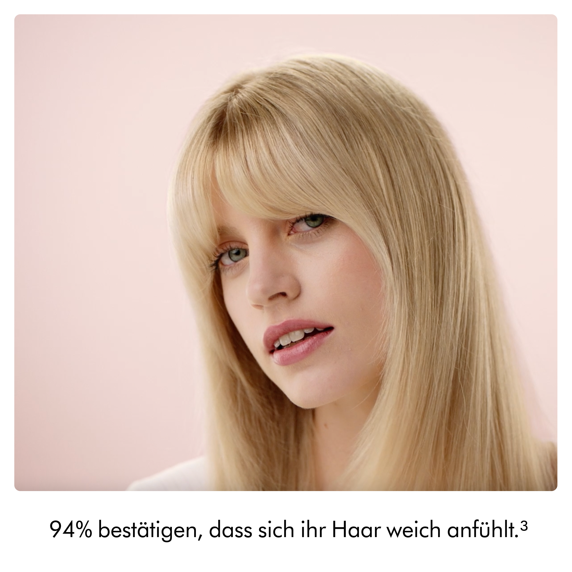Eine blonde Frau mit Pony und rosa Lippenstift vor hellem Hintergrund.