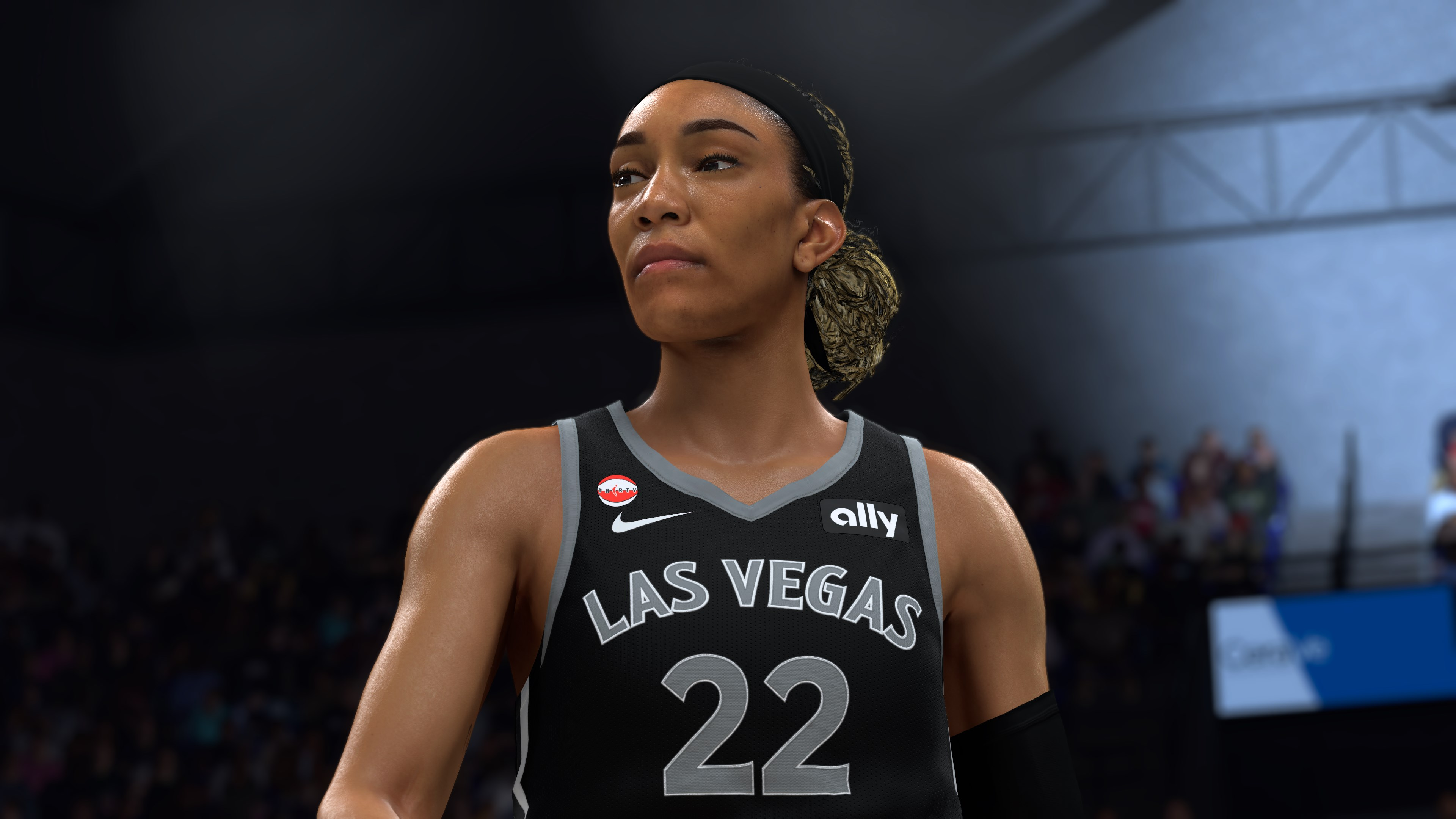 Una giocatrice di basket con maglia nera di Las Vegas e numero 22 guarda concentrata in lontananza.