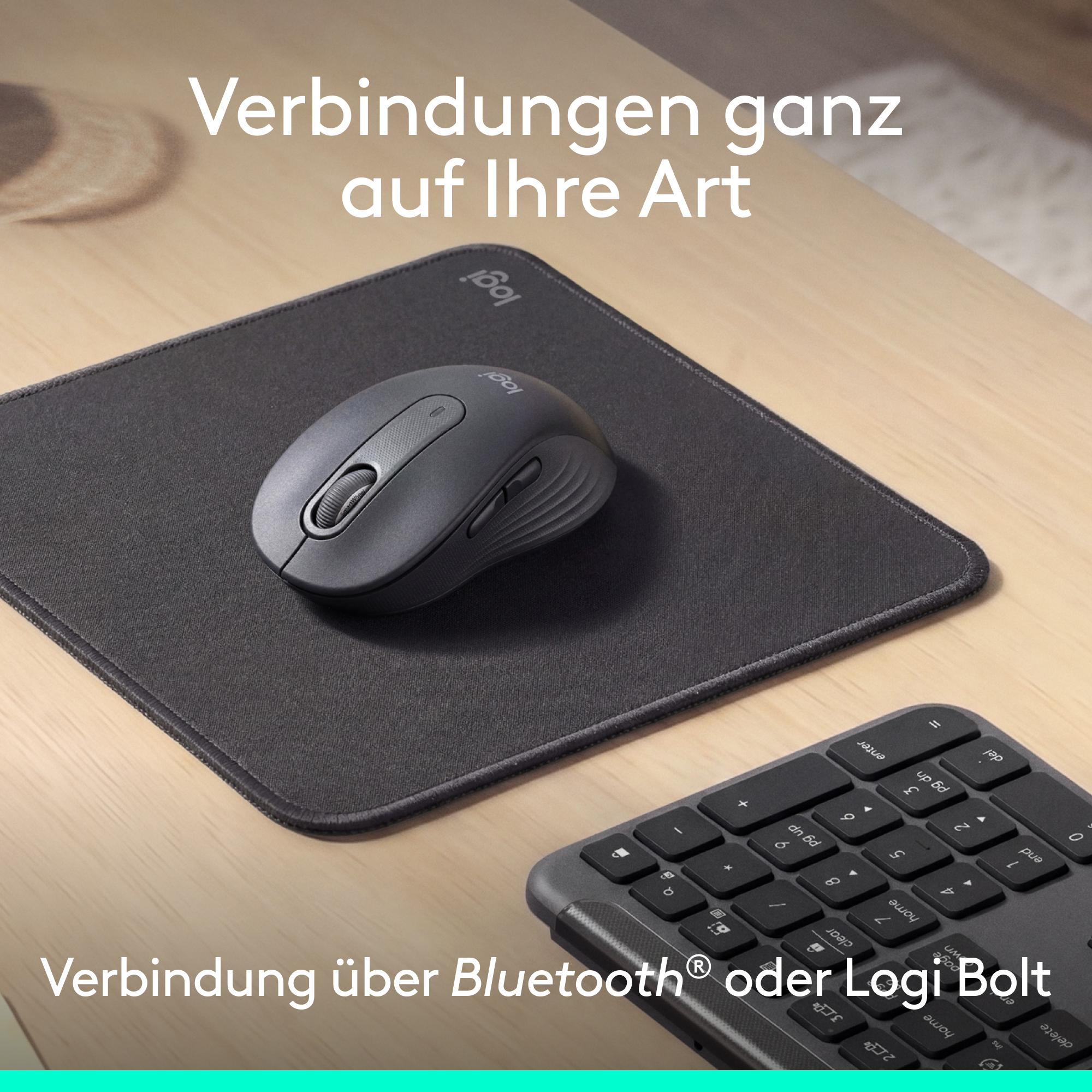 Eine graue Computermaus auf einem schwarzen Mauspad auf einem Holzschreibtisch mit deutscher Textüberlagerung.