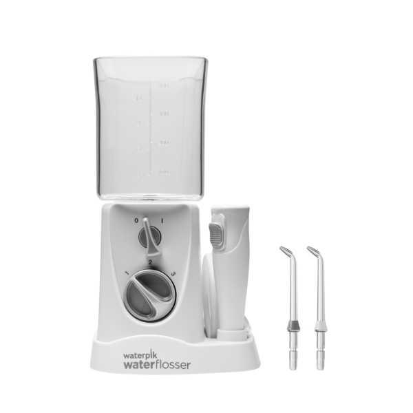 Un irrigador bucal Waterpik blanco con depósito transparente, un mango y dos boquillas en una base blanca.