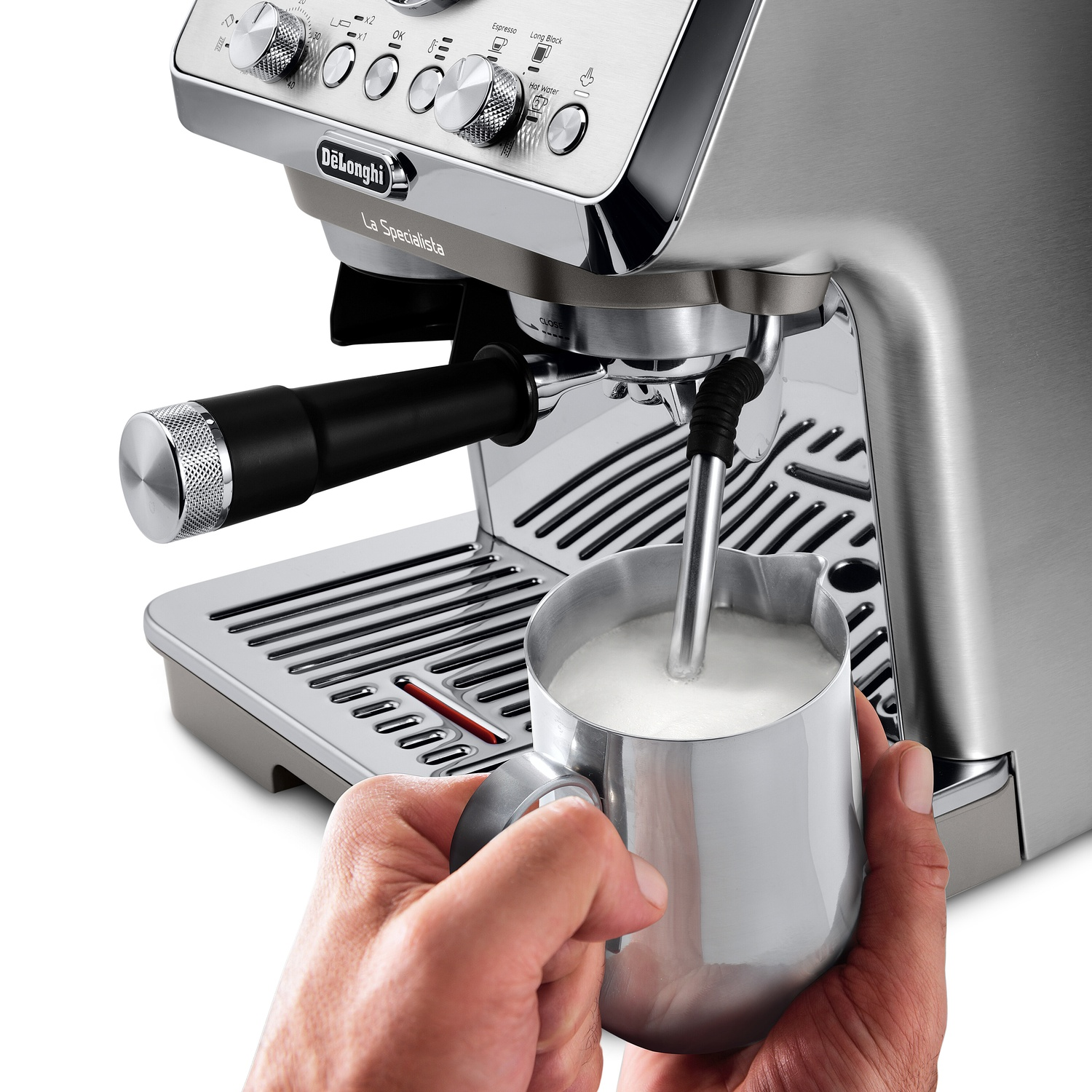Handen houden een roestvrijstalen kan vast terwijl melk opschuimt via het stoompijpje van een DeLonghi.