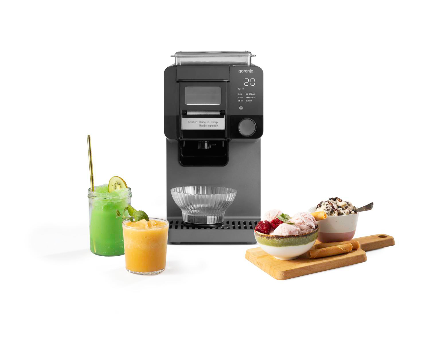Eine Gorenje-Eismaschine in der Mitte, flankiert von grünen und orangen Smoothies sowie Schüsseln voller Eiscreme.