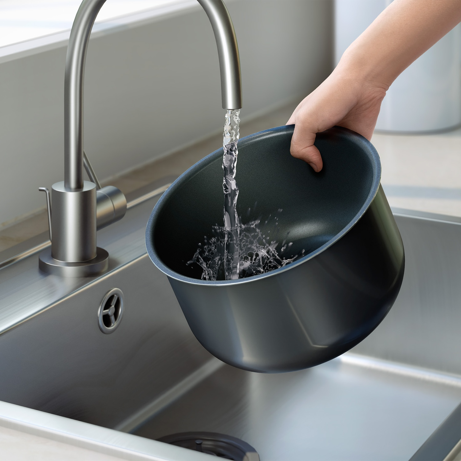 A hand holds a black pot under running water in a stainless steel sink.
