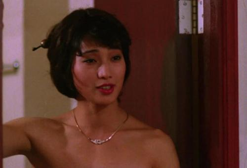 Eine asiatische Frau mit schwarzem Haar und Kette steht im Innenbereich.
