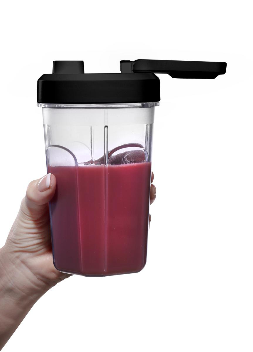 Eine Hand hält einen klaren Plastikbecher gefüllt mit einem rosa Smoothie gegen einen weißen Hintergrund.