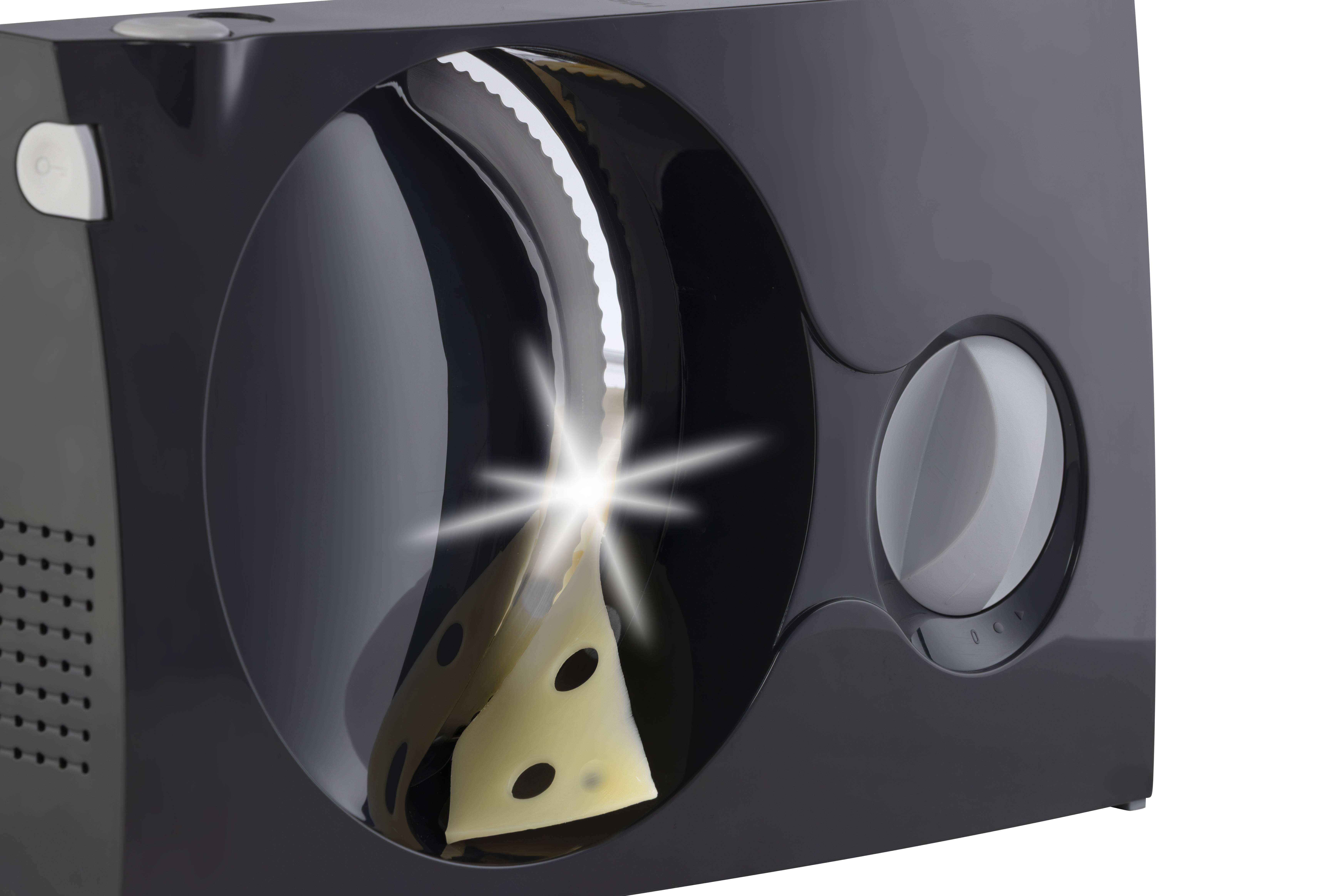 Eine schwarze elektrische Aufschnittmaschine schneidet Schweizer Käse, ein heller Lichtblitz ist zu sehen.
