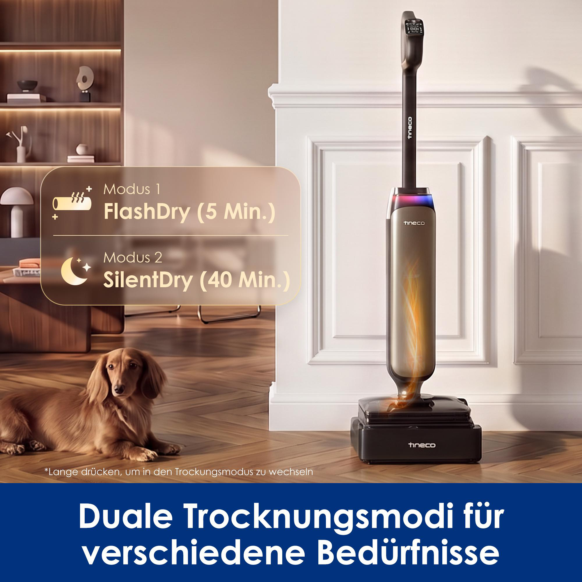 Ein schwarzer kabelloser Staubsauger steht auf einem Holzboden in einer Wohnung, ein Hund liegt daneben.