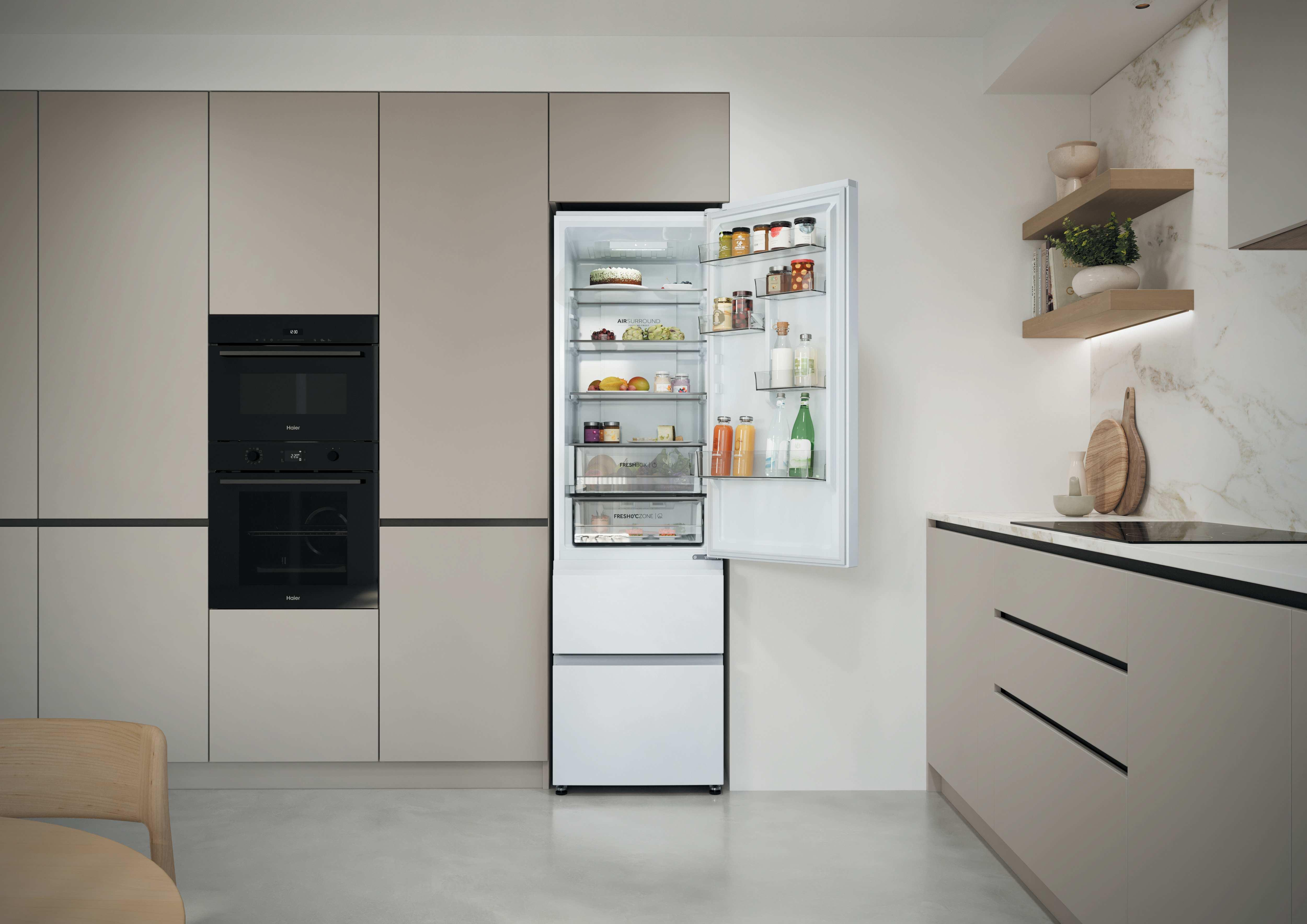 Cocina moderna con un frigorífico blanco empotrado, abierto para mostrar los alimentos almacenados.