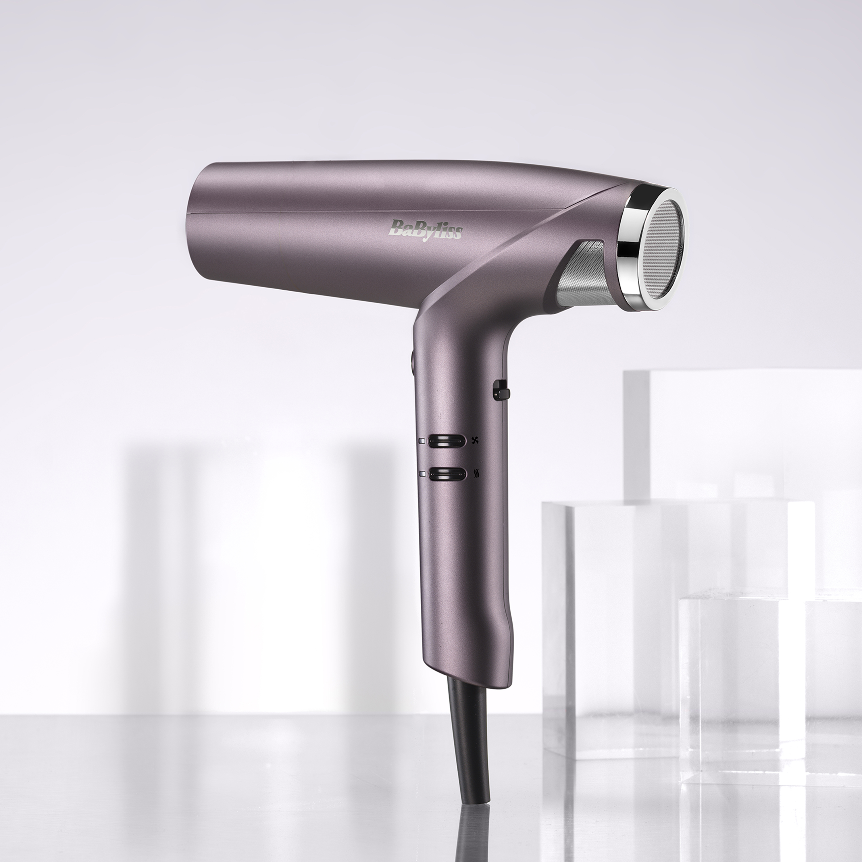 Ein eleganter, metallic-violetter BaByliss-Haartrockner steht aufrecht auf einer reflektierenden Oberfläche.