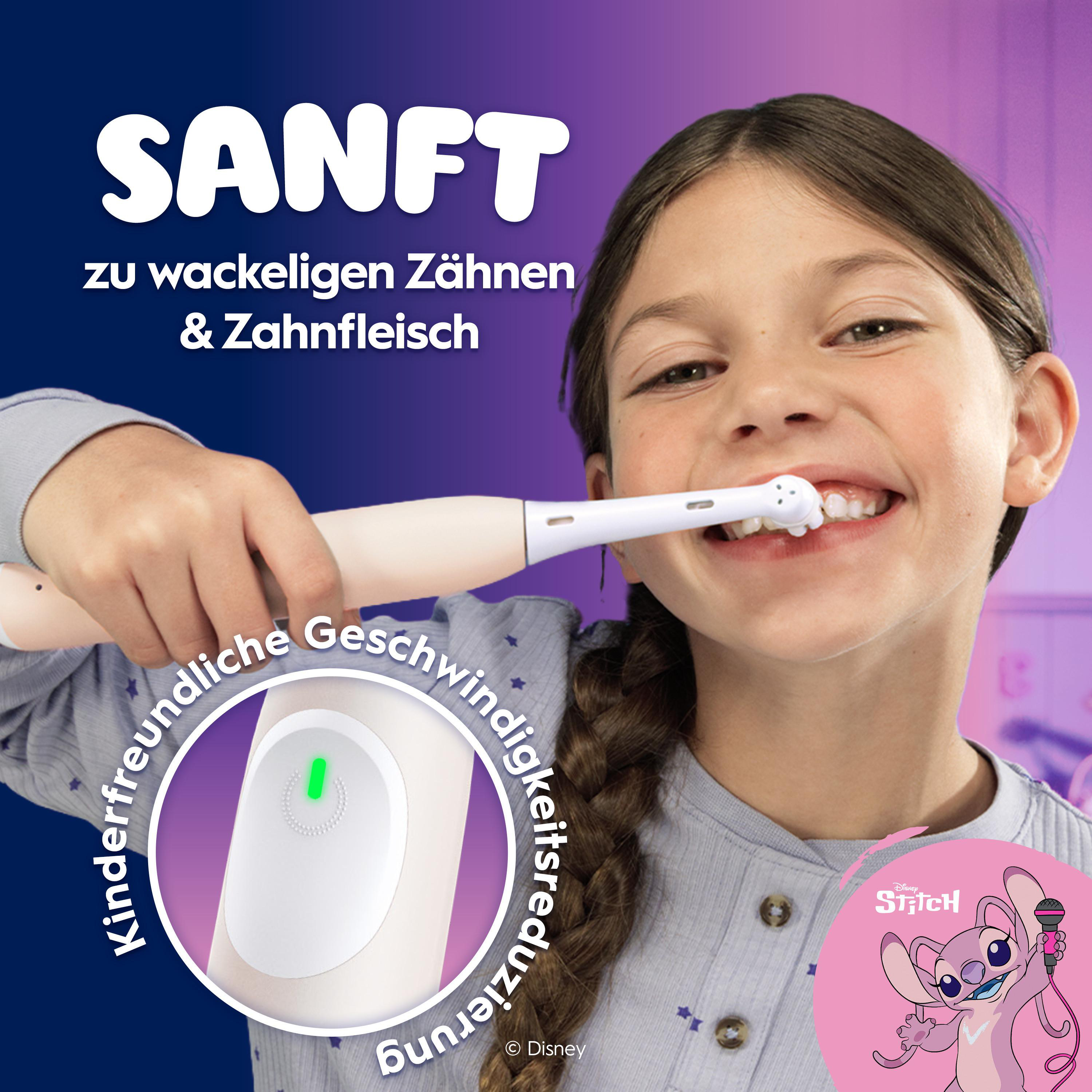 Ein junges Mädchen lächelt, während es sich mit einer elektrischen Zahnbürste die Zähne putzt.