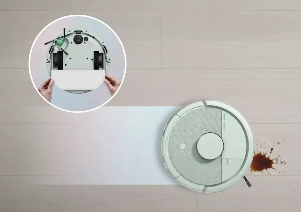 Un robot aspirador limpia un suelo de madera, con una imagen insertada que muestra su parte inferior.