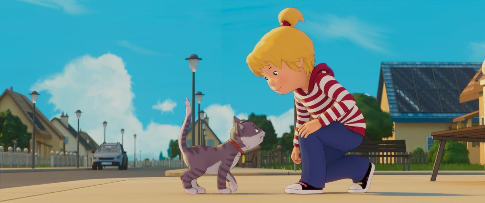 Ein blondes Mädchen in gestreiftem Pullover kniet auf dem Gehweg und blickt auf eine graue gestreifte Katze.