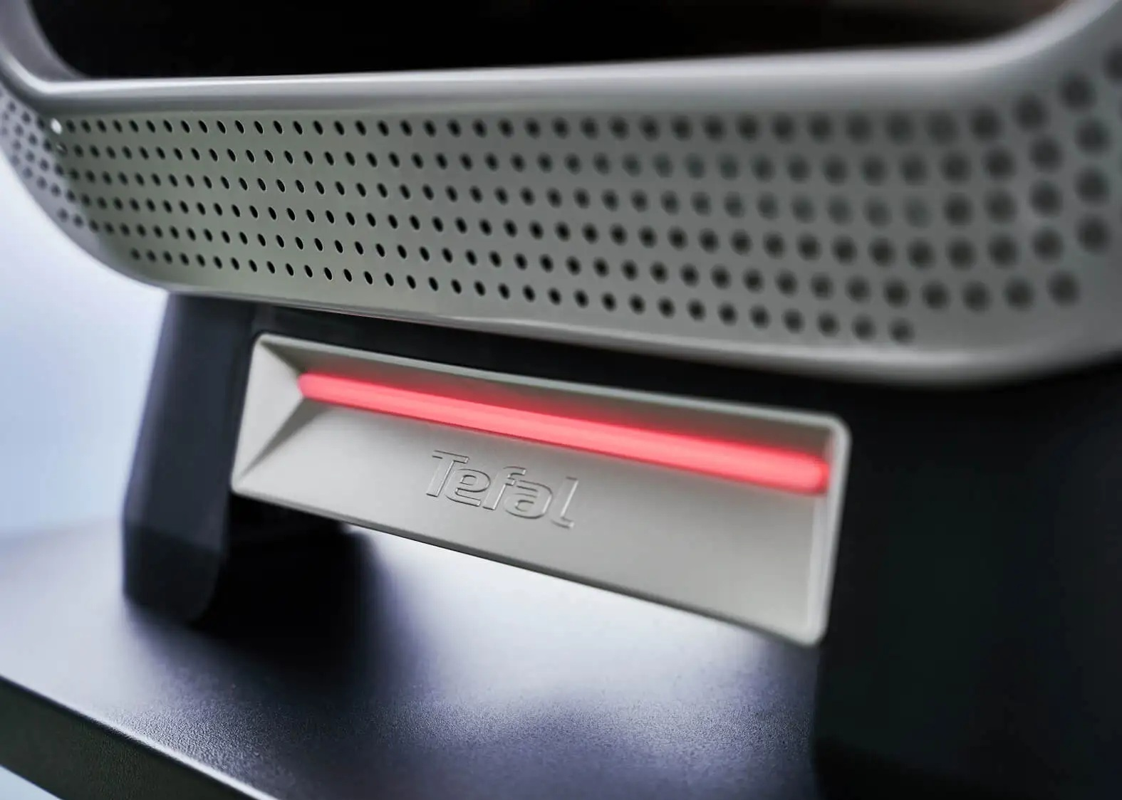 Urządzenie Tefal z perforowaną szarą obudową i świecącym czerwonym paskiem LED.