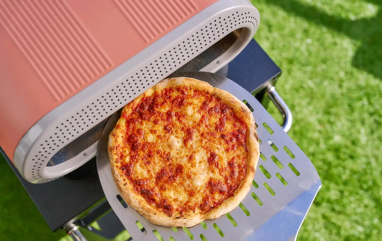 Świeża pizza na łopacie przed piecem do pizzy na zewnątrz.