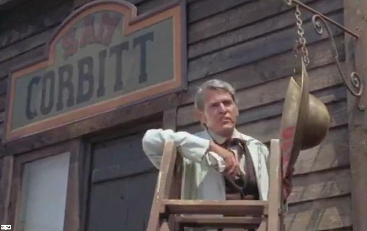 Ein Mann auf einer Holzleiter vor einem Gebäude mit einem großen 'CORBITT'-Schild.