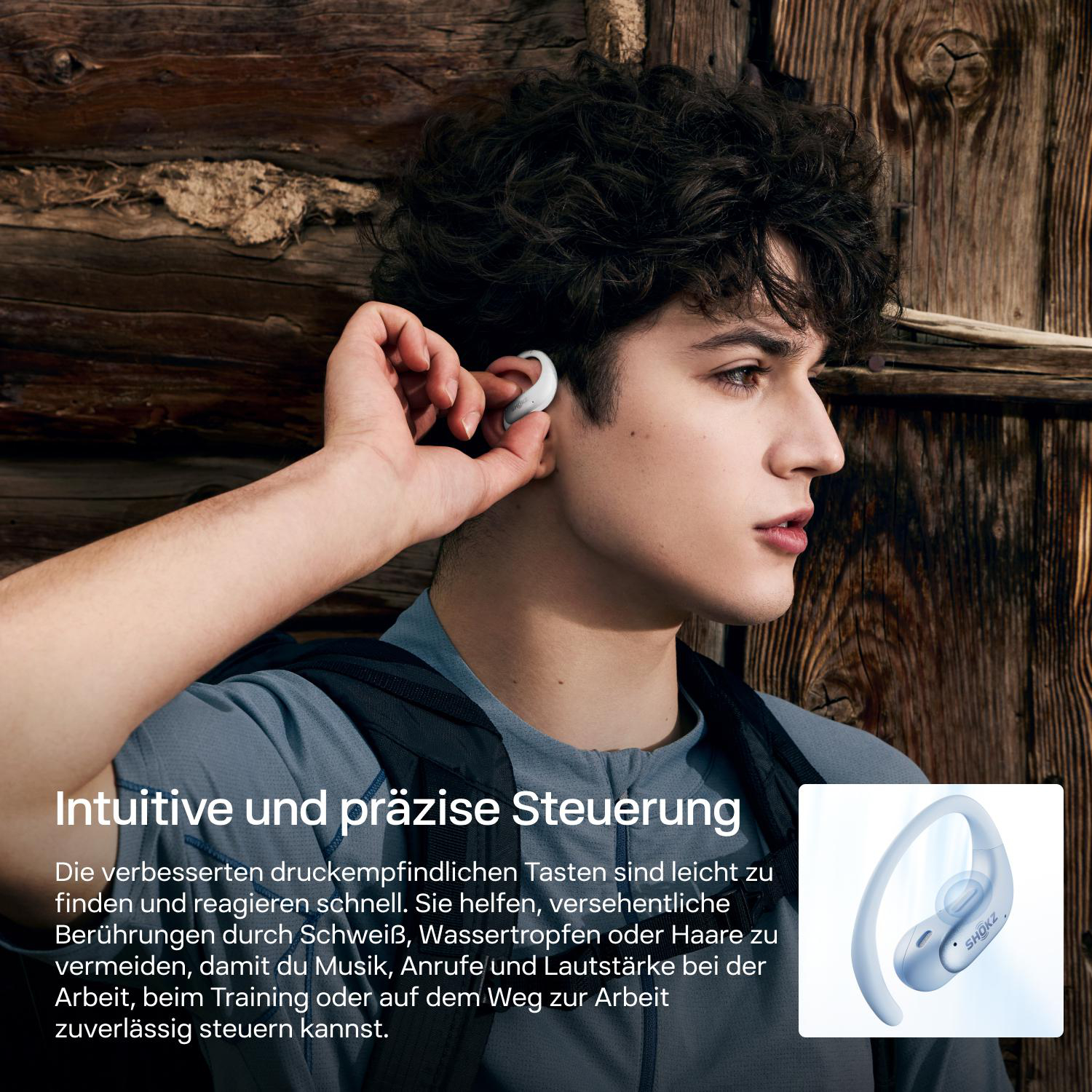 Ein junger Mann setzt sich einen weißen Ohrhörer ein, vor einer Holzwand mit Text und Produktbild.
