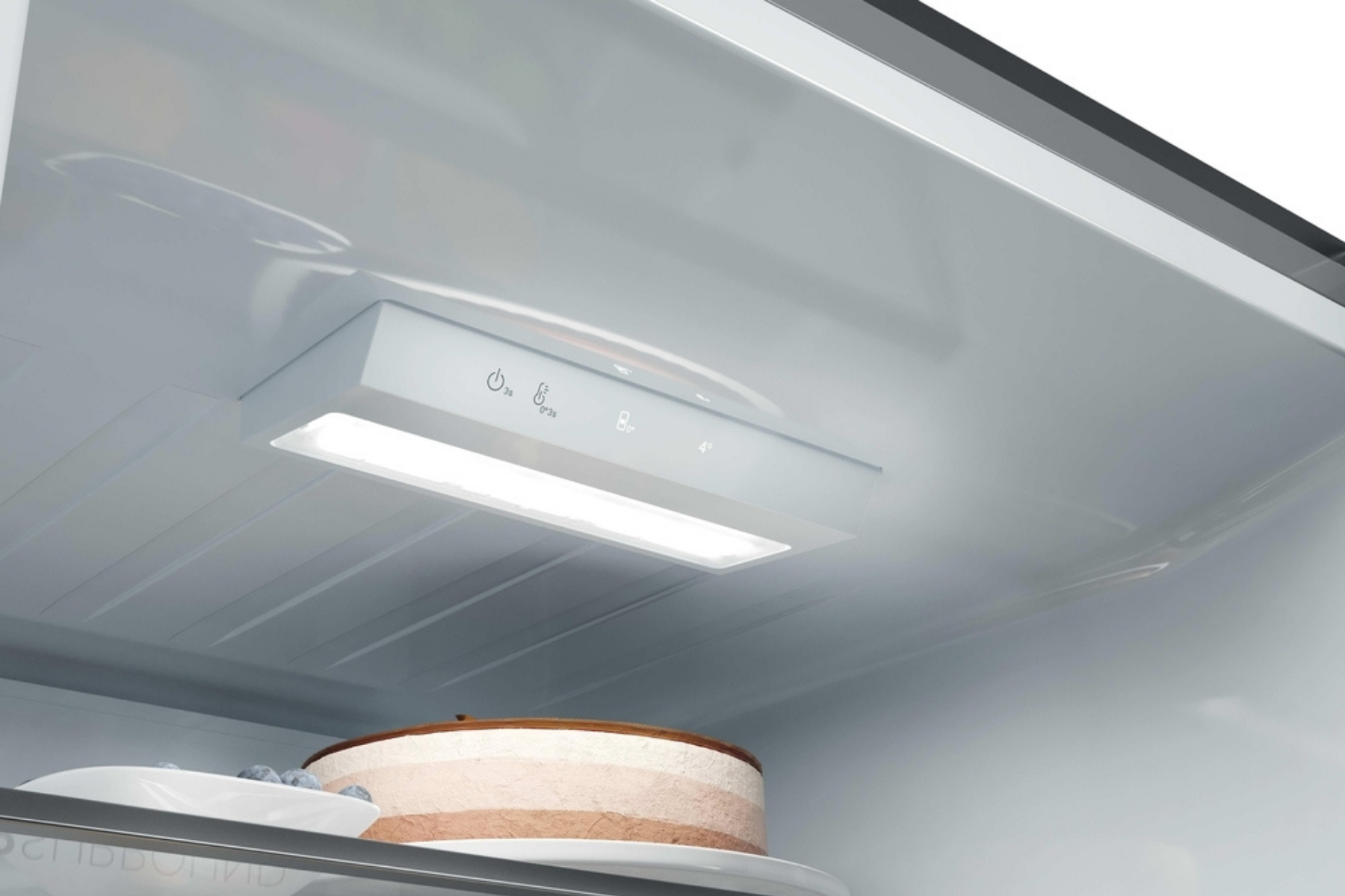 Luz interior y panel de control táctil en el techo de un refrigerador moderno, con alimentos en el estante.