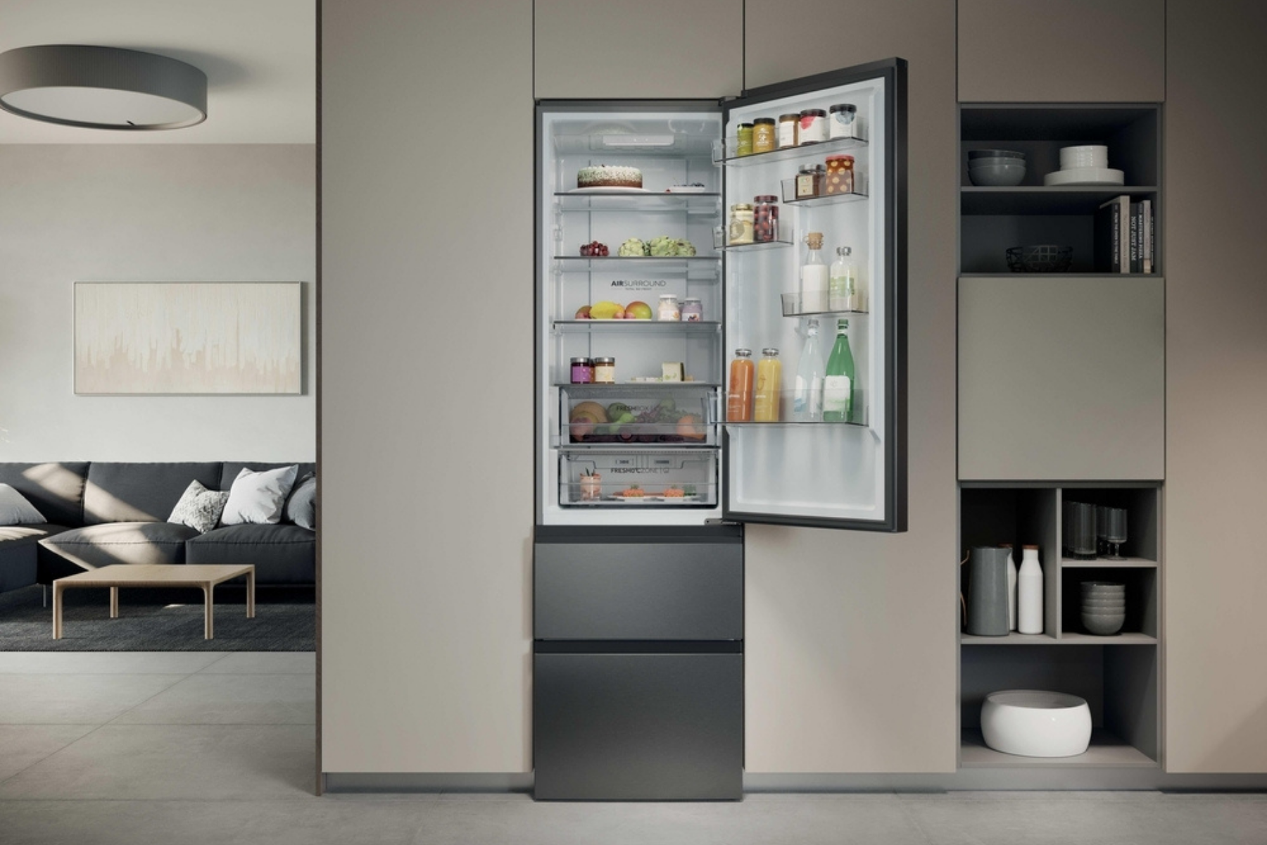 Un refrigerador empotrable gris abierto en una cocina moderna muestra estantes llenos con una sala visible al fondo.