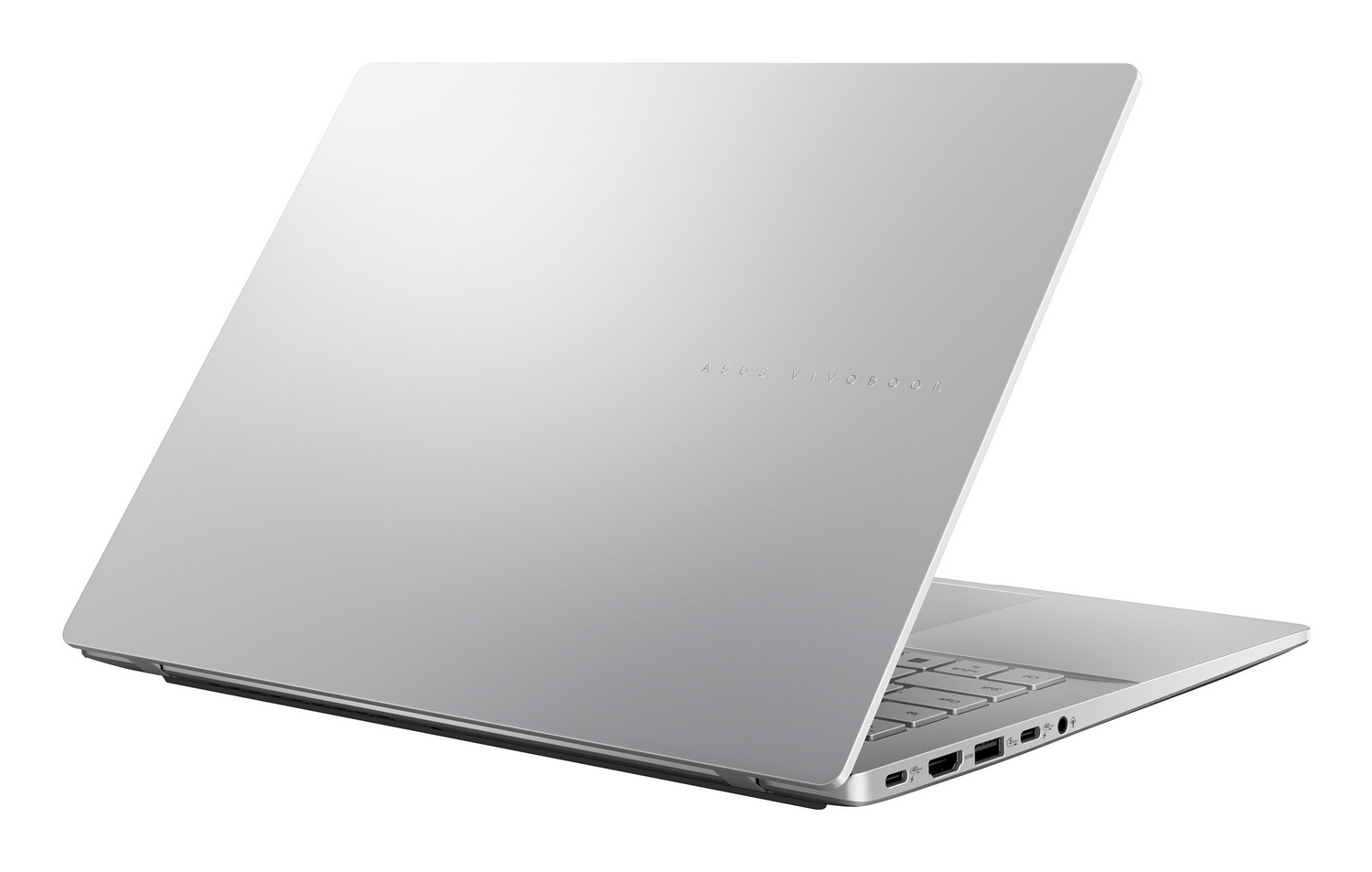 Un portátil plateado Asus Vivobook está abierto sobre fondo blanco, puertos laterales visibles.