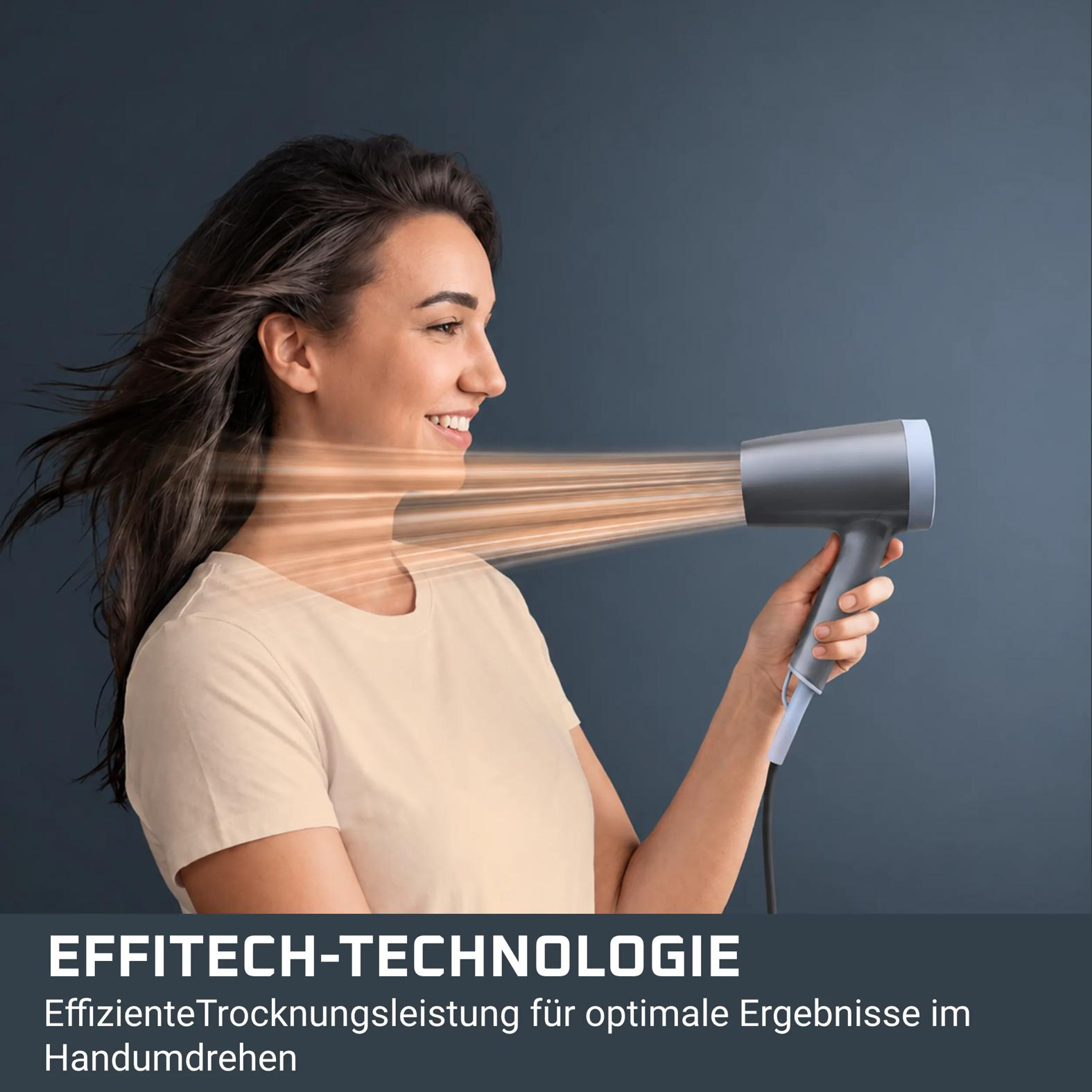 Eine Frau trocknet ihre Haare mit einem grauen Föhn, während der Wind ihr Haar weht.