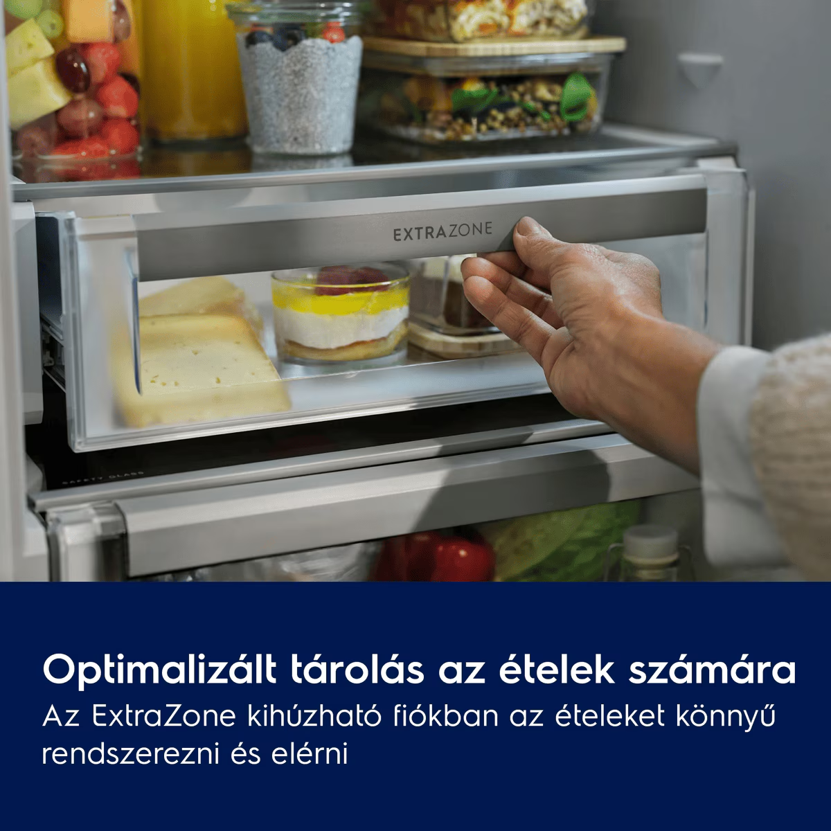 Egy kéz kinyit egy ExtraZone hűtőfiókot sajttal és desszertekkel, alatta szöveggel.