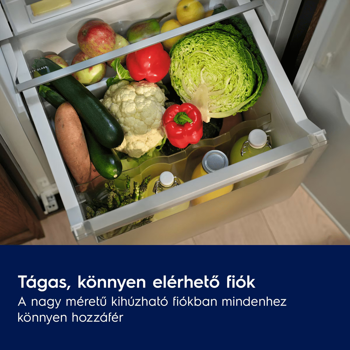 Nyitott hűtőfiók tele friss zöldséggel, gyümölccsel és palackokkal.
