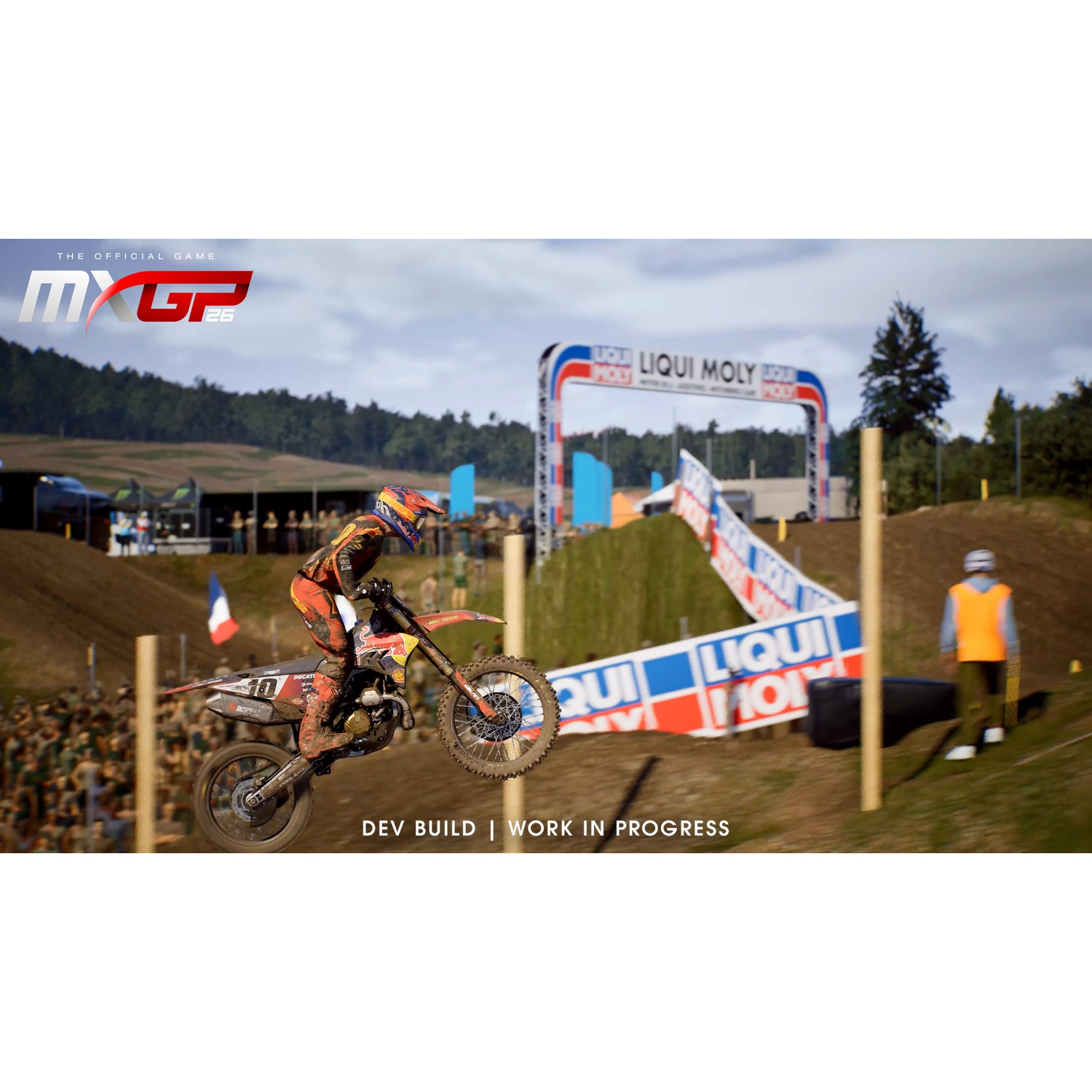 Un pilote de motocross saute en moto par-dessus une rampe de terre sur une piste avec des spectateurs.