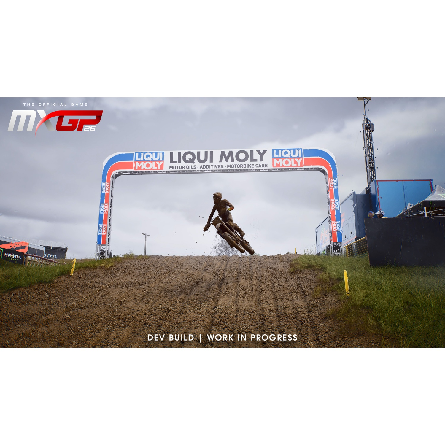 Un pilote de motocross saute au-dessus d'une colline boueuse sous un ciel couvert.