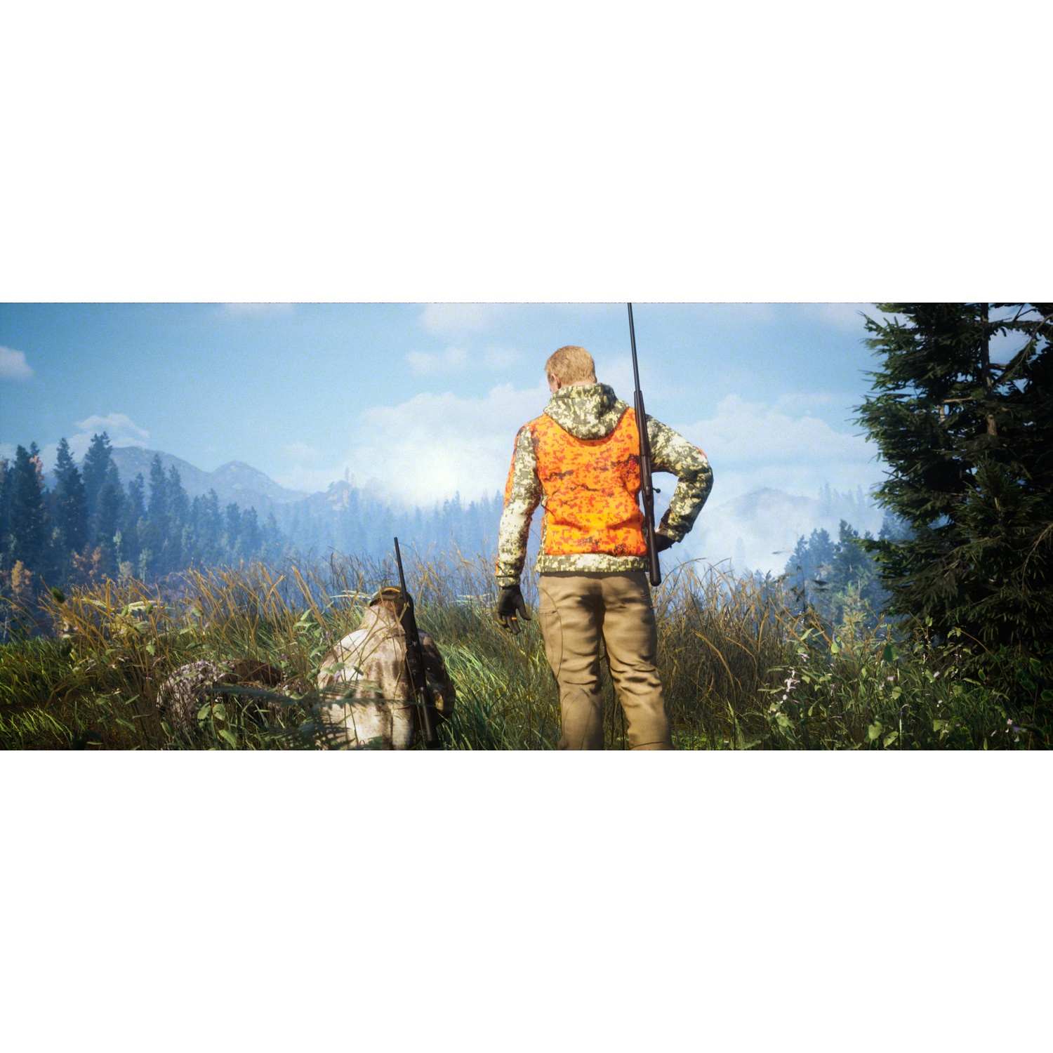 Un chasseur en camouflage et gilet orange dans un champ herbeux avec un fusil, montagnes et arbres en fond.
