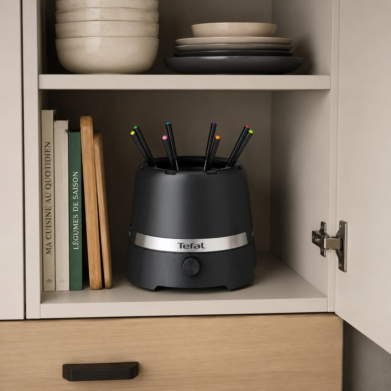 A black Tefal appliance holder with colorful utensils on a kitchen shelf beside cookbooks and dishes.