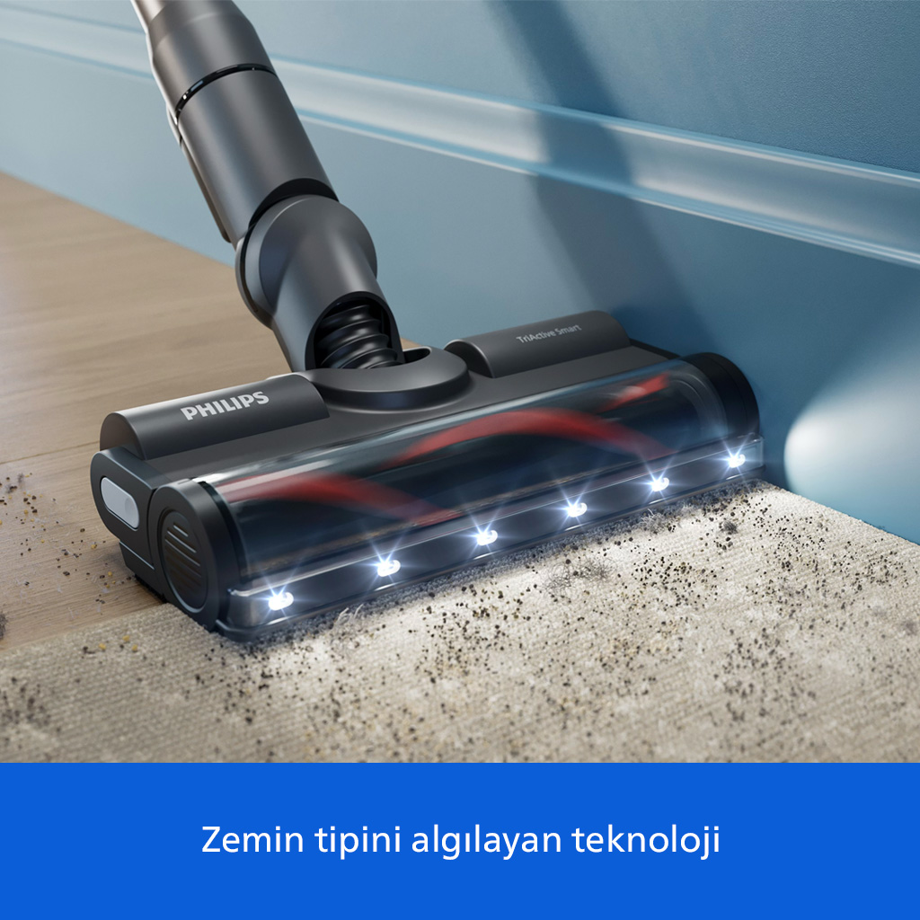 Mavi duvar önündeki tozlu halıyı temizleyen LED ışıklı siyah Philips süpürge başlığı.