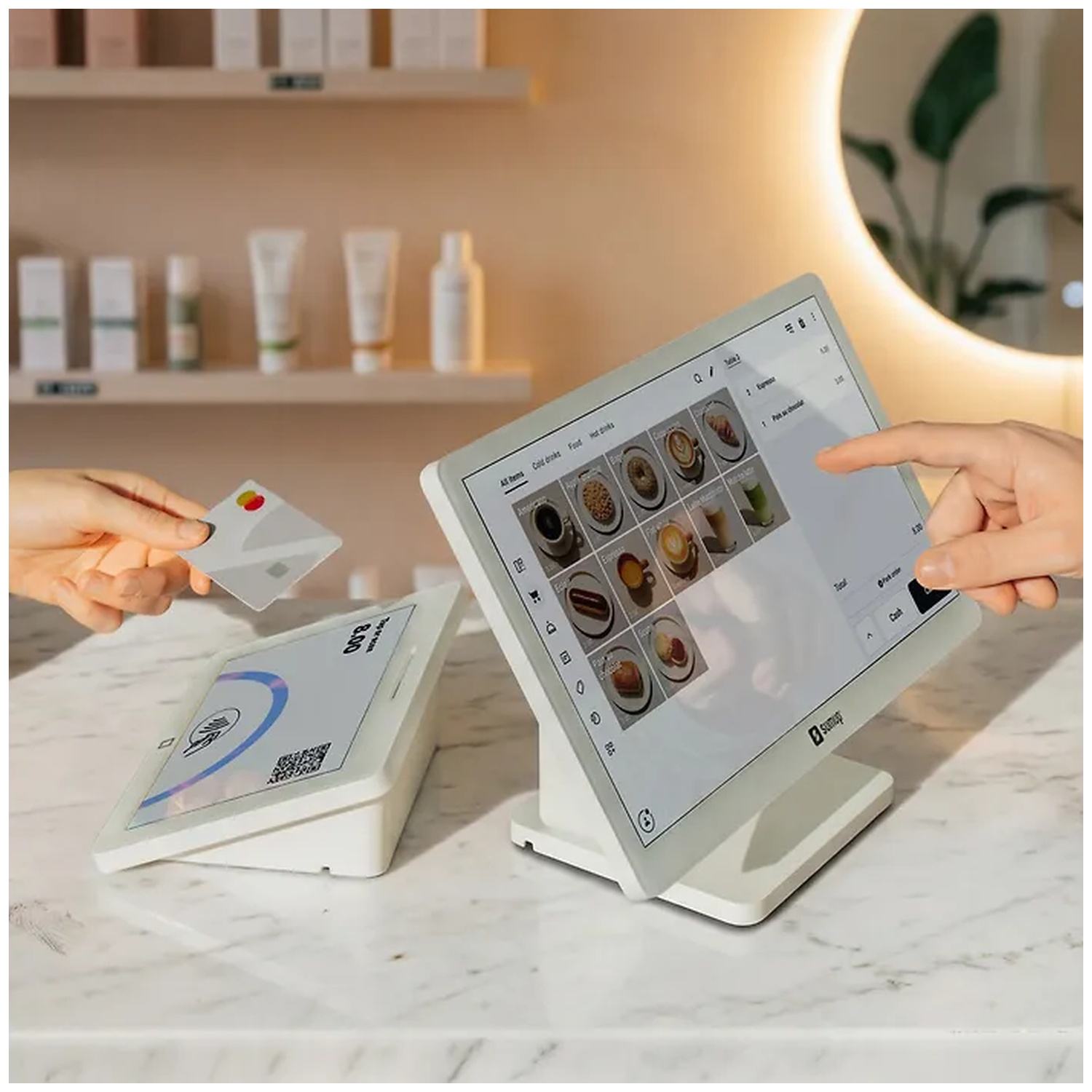 A POS terminal on a counter while one hand holds a credit card and another touches the screen.