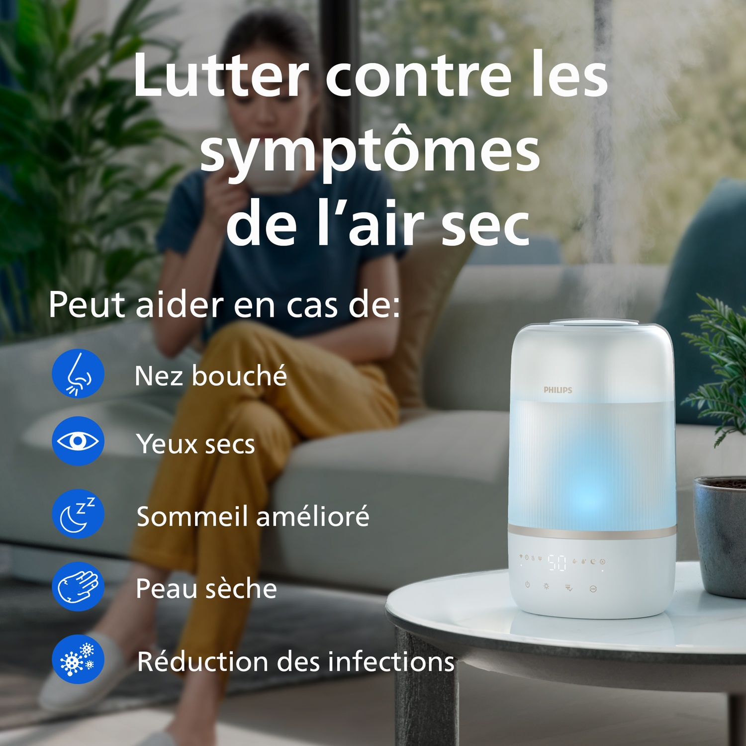 Un humidificateur Philips sur une table basse dans un salon, avec une femme assise à l'arrière-plan.