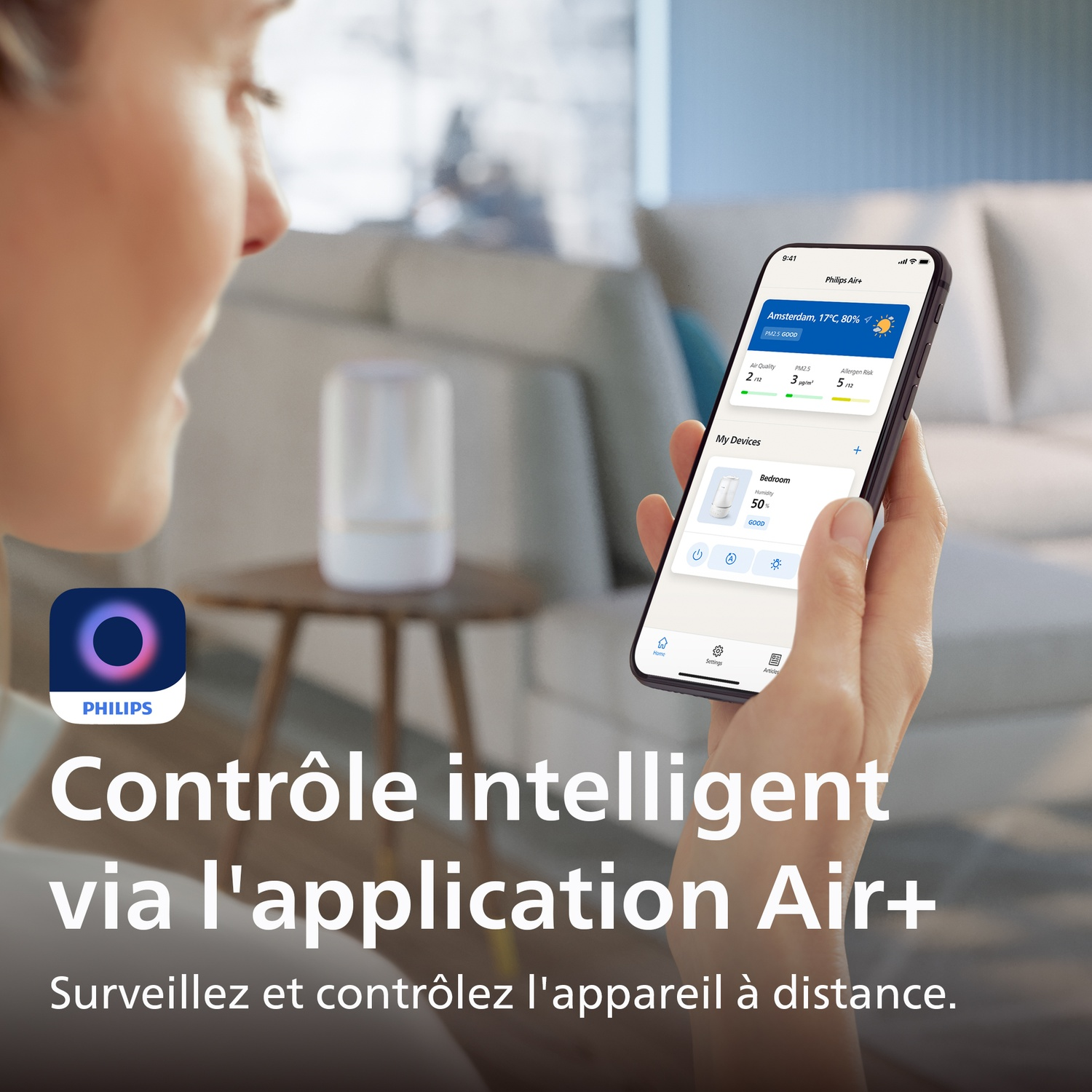 Personne tenant un smartphone affichant l'application Philips Air+ dans un salon moderne.
