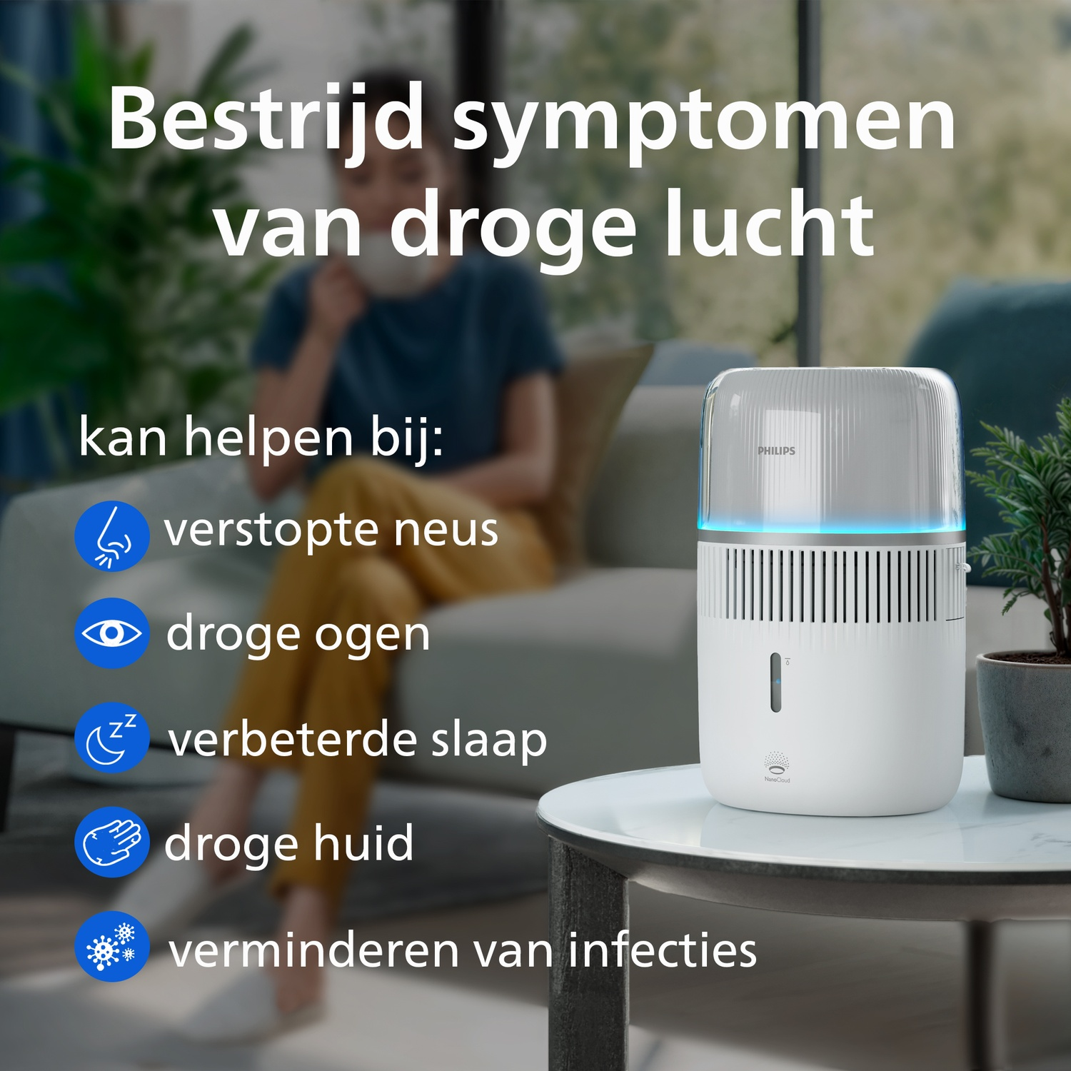 Een Philips luchtbevochtiger op een salontafel, met een vrouw op de bank in de achtergrond.