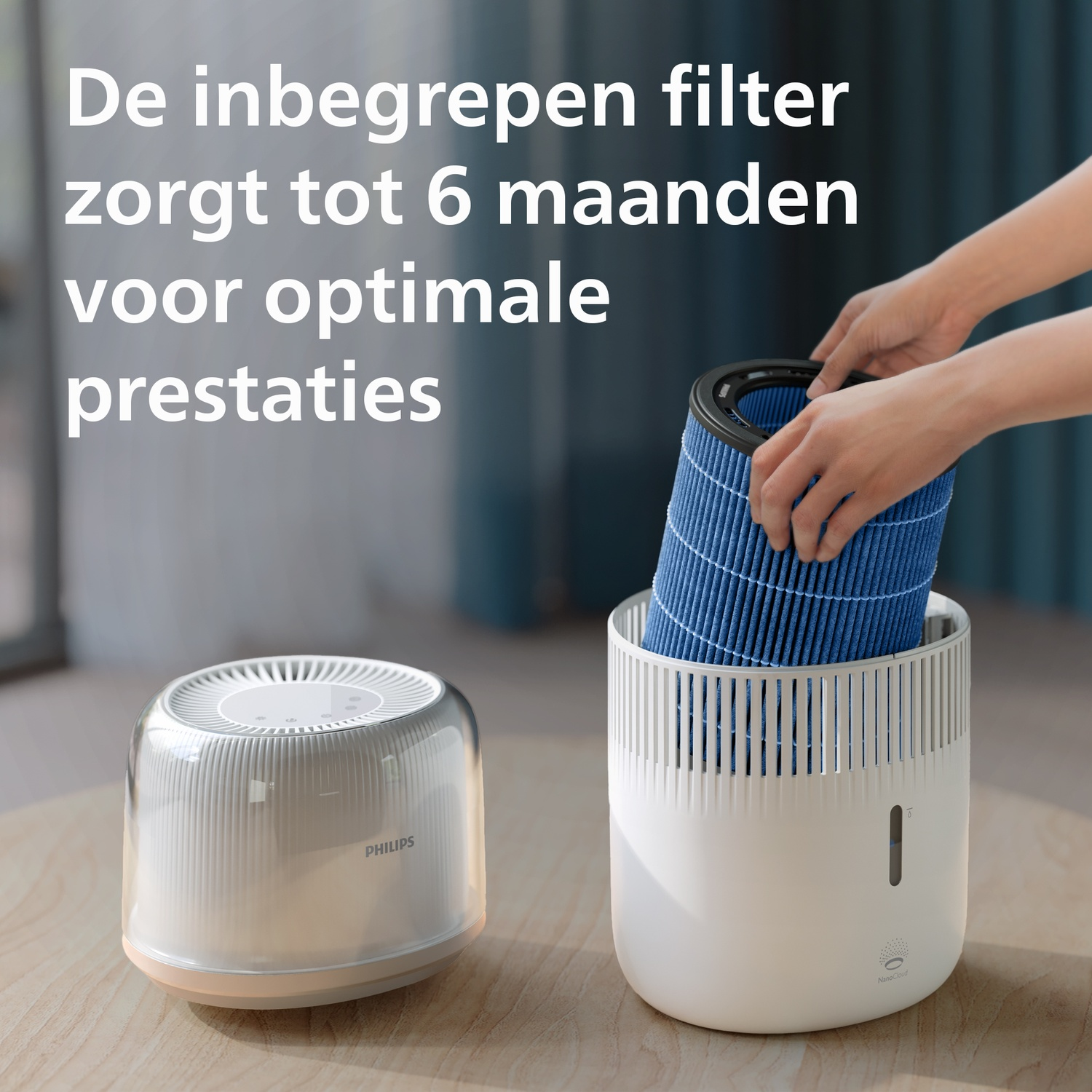 Handen plaatsen een blauw geplooid filter in een witte Philips luchtreiniger op een houten tafel.