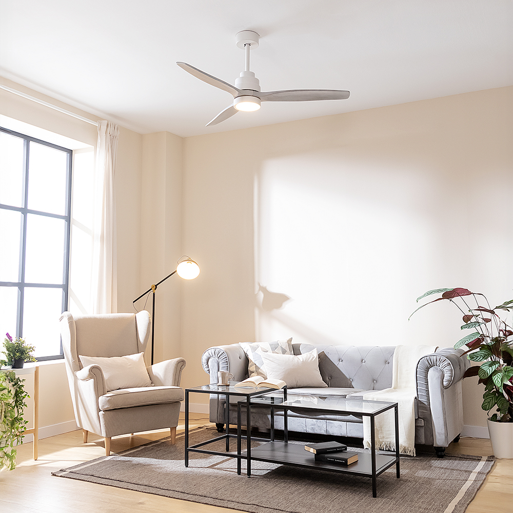 Sala con sofá gris, sillón, ventilador de techo, mesas de vidrio y grandes ventanas con luz natural.